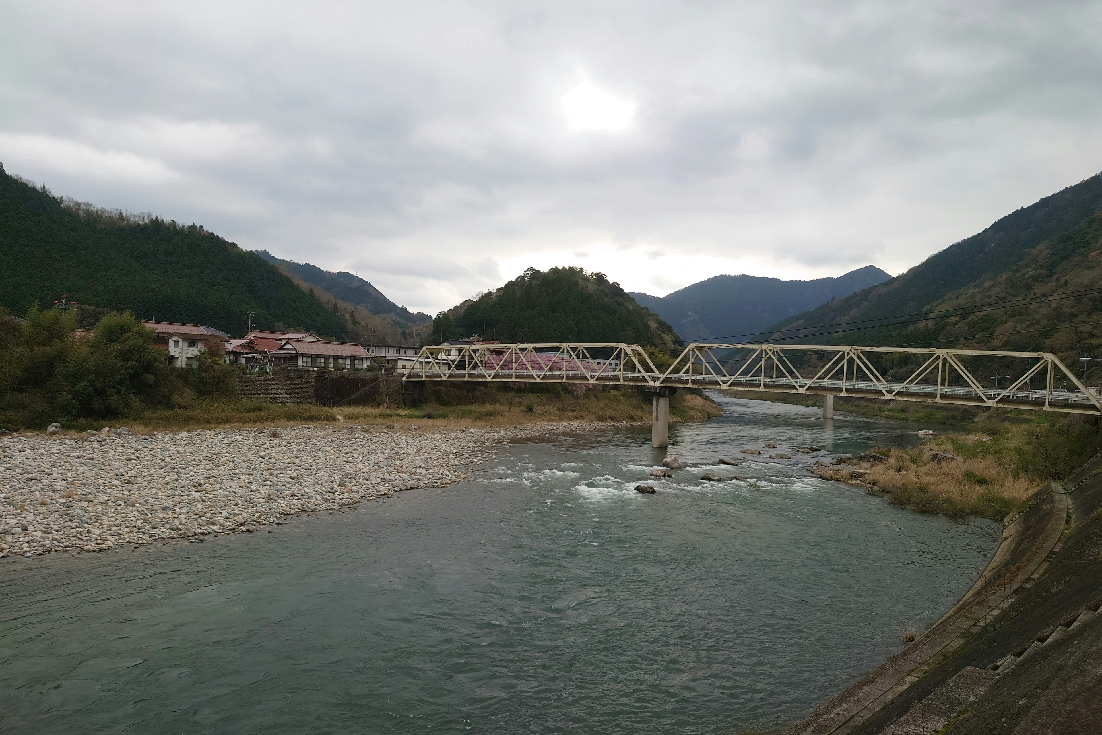 Landschaft mit einer Stahlbrücke über einem Fluss und Bergen im Hintergrund