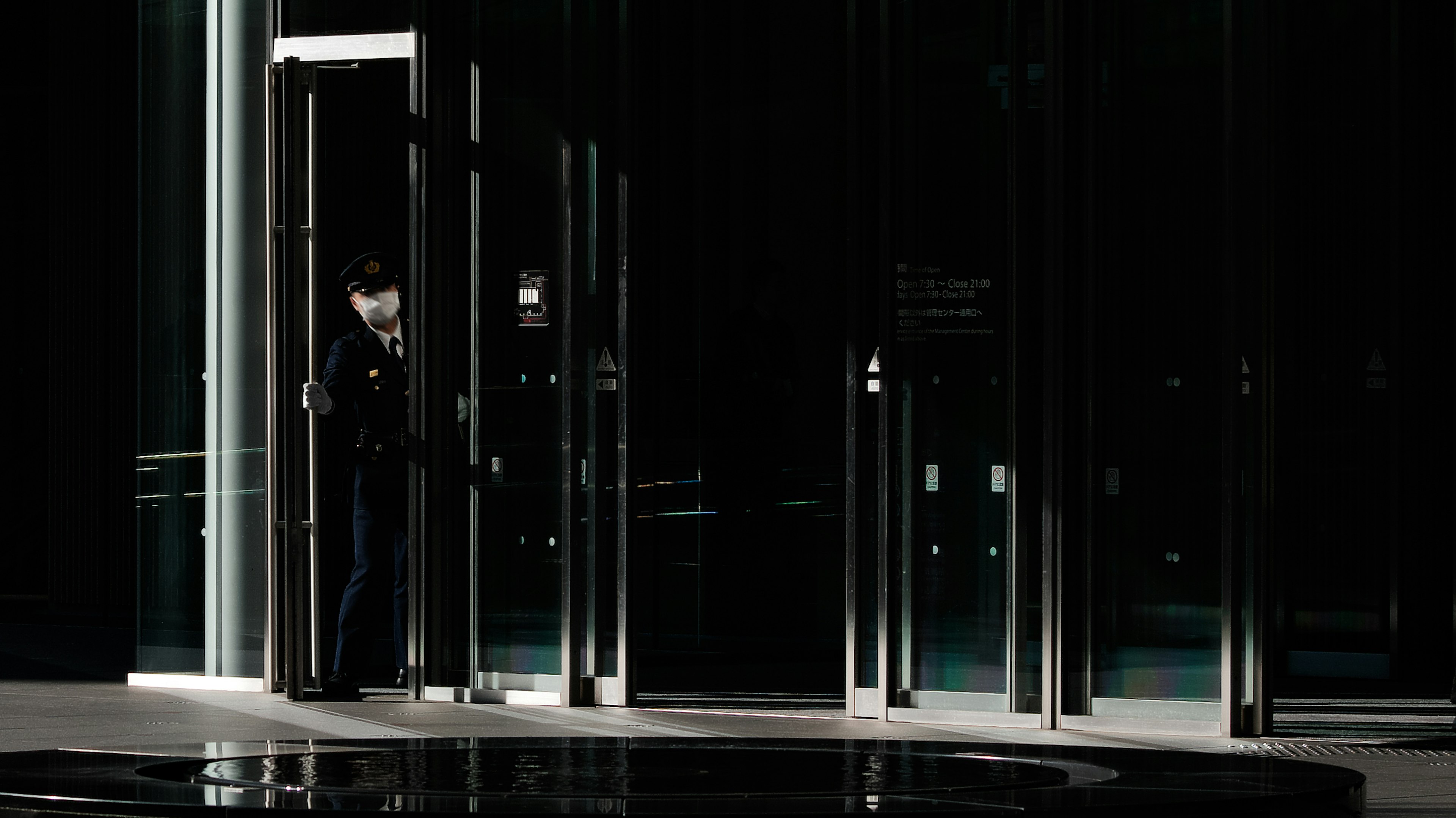 Security guard operating revolving door in a dark lobby