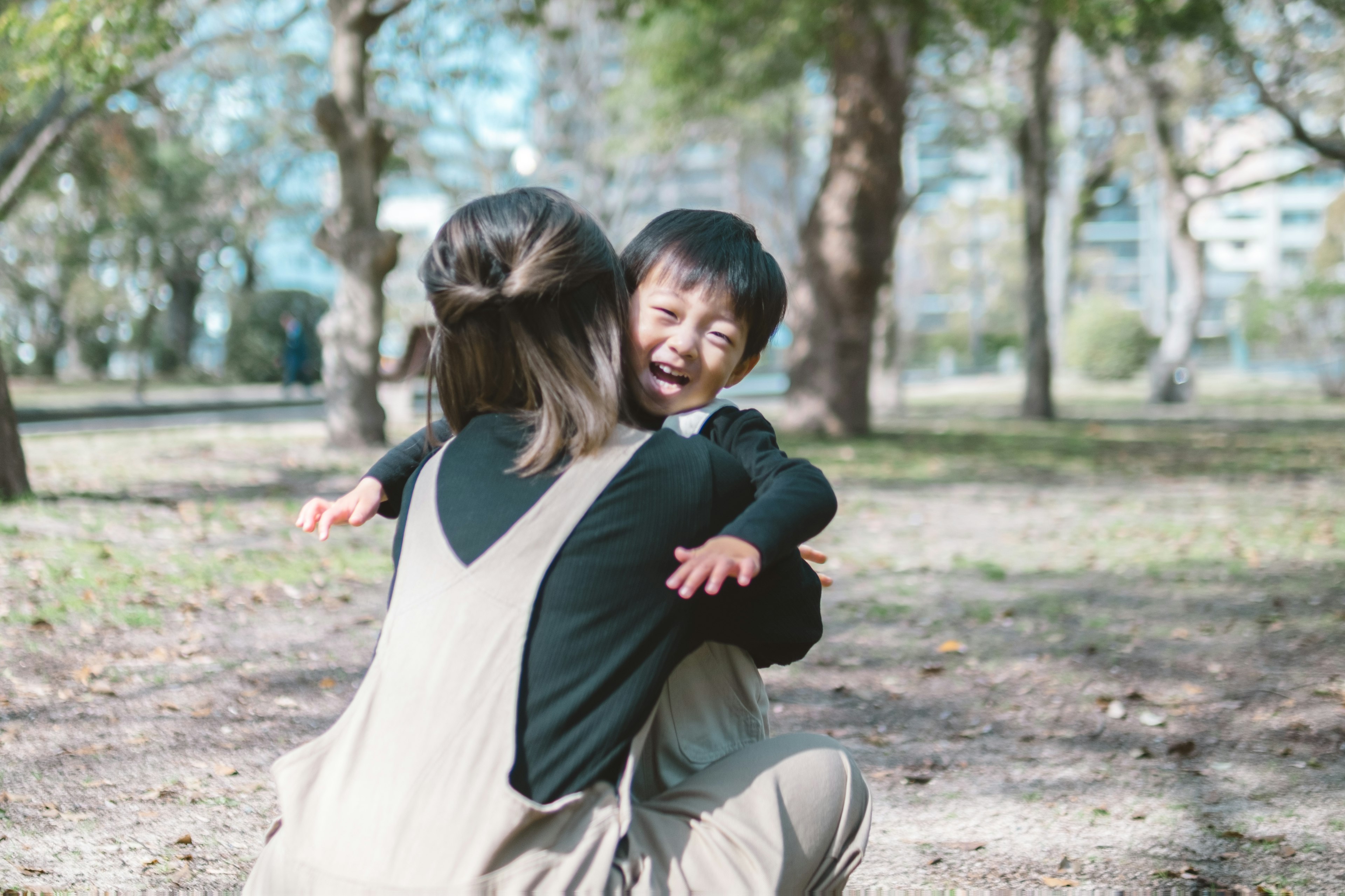 A mother hugging her laughing child in a park