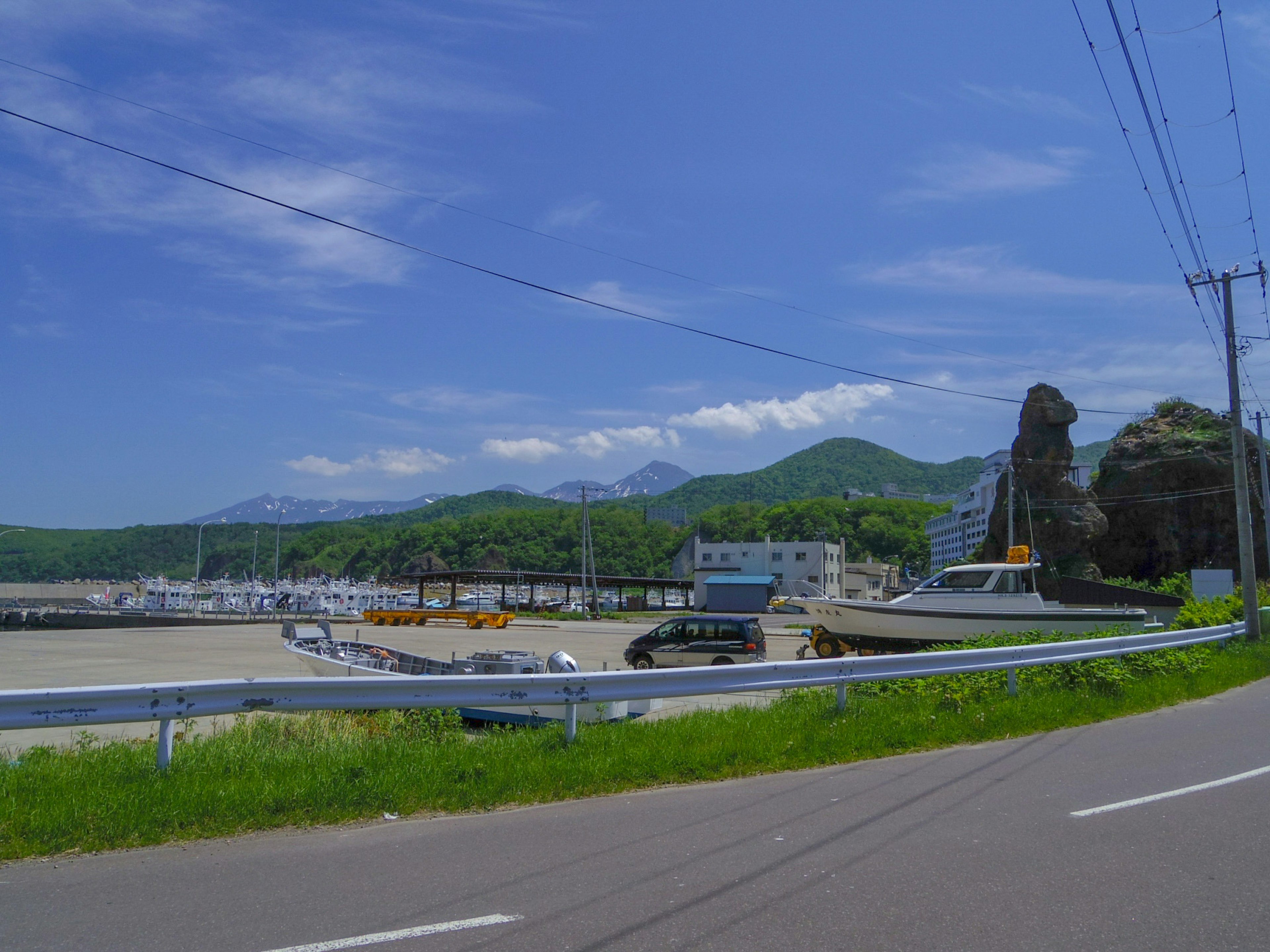 ทิวทัศน์ของท่าเรือใต้ท้องฟ้าสีฟ้าพร้อมภูเขาสีเขียวและเรือที่มองเห็นได้