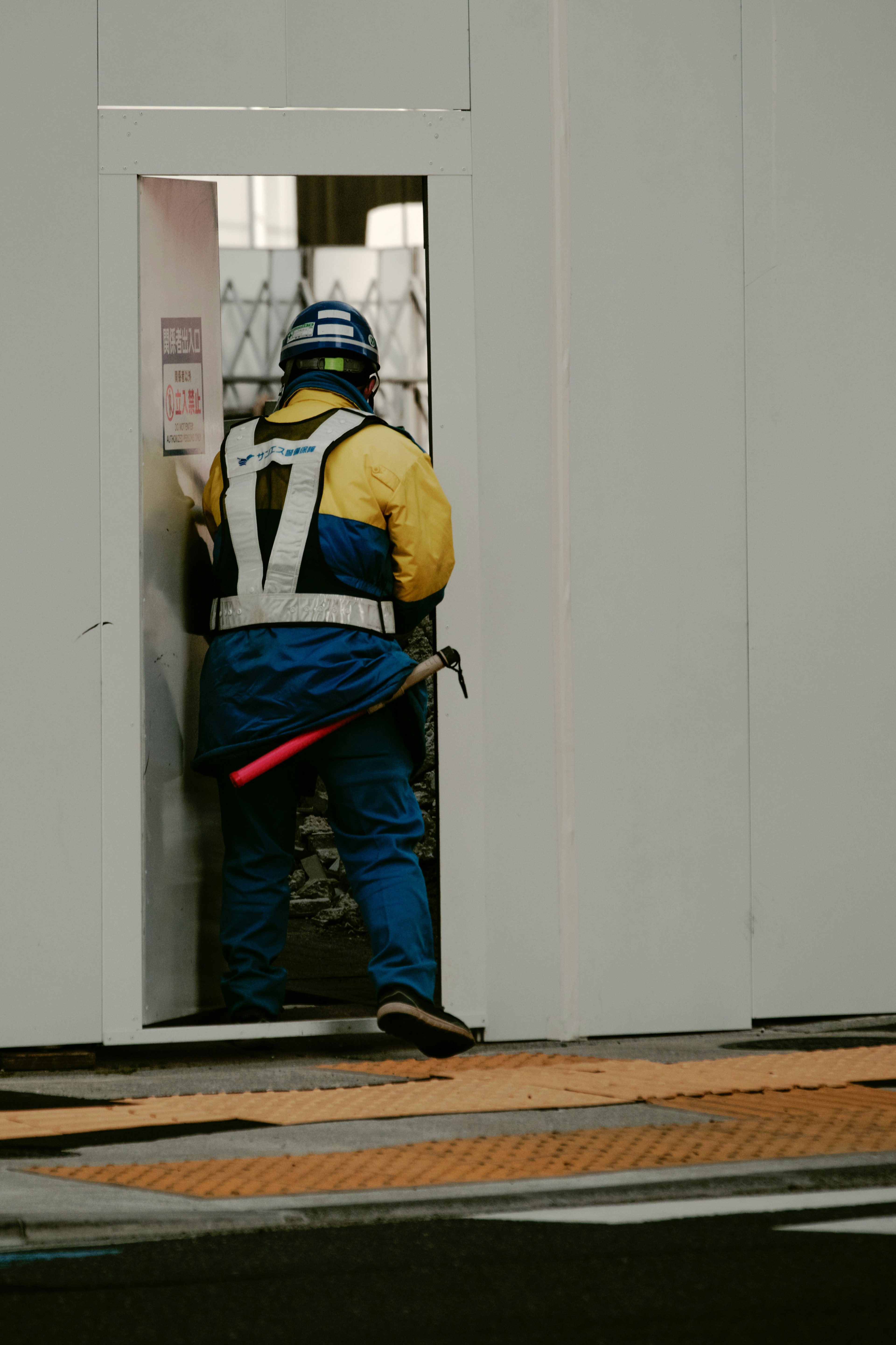 Un lavoratore in giubbotto di sicurezza davanti a una porta bianca