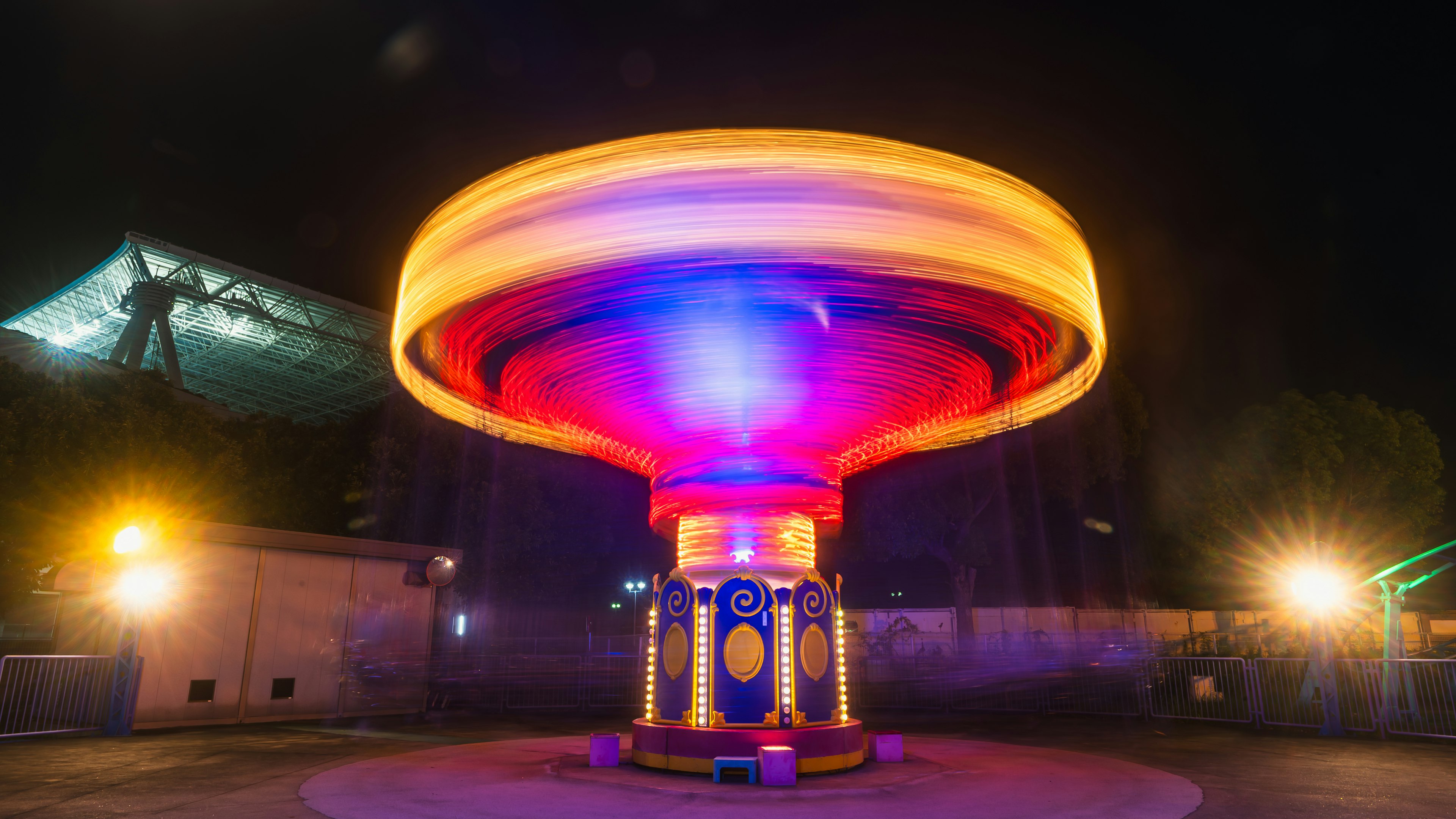 Spinning amusement park ride at night with bright colors and lights