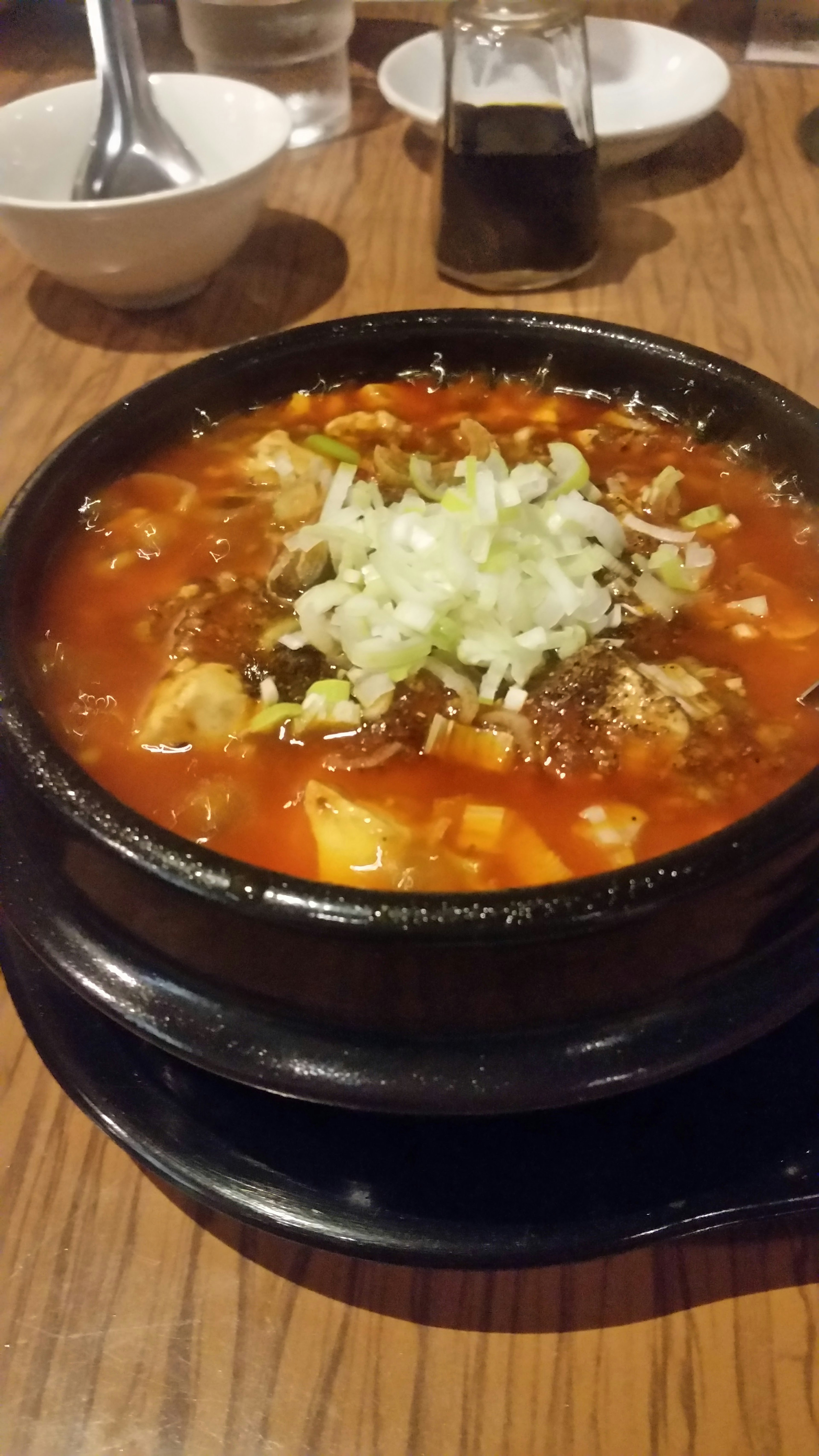 Spicy soup dish served in a black stone pot with vegetables