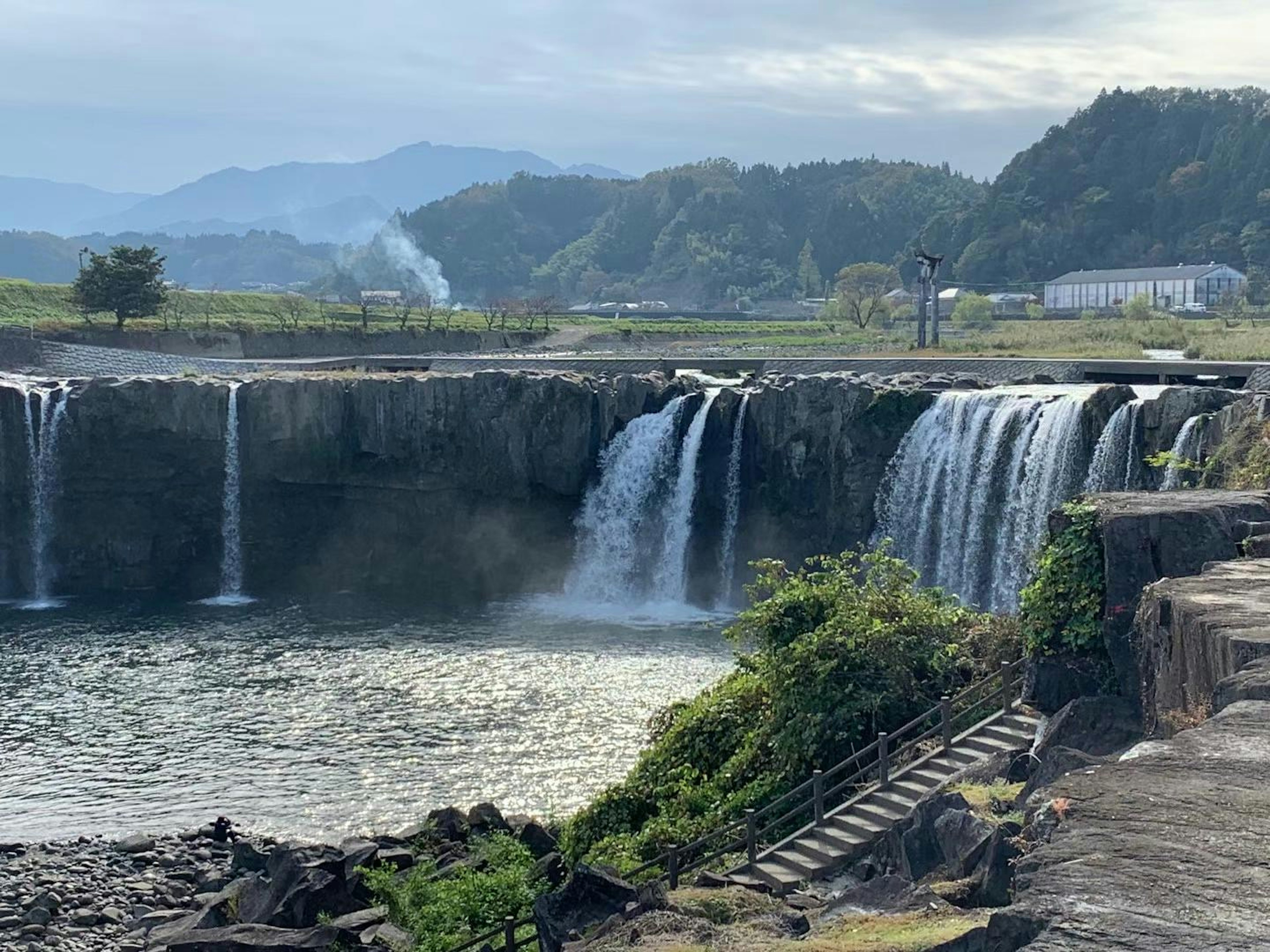 美しい滝が流れる風景 山や雲の背景 緑の植物が映える