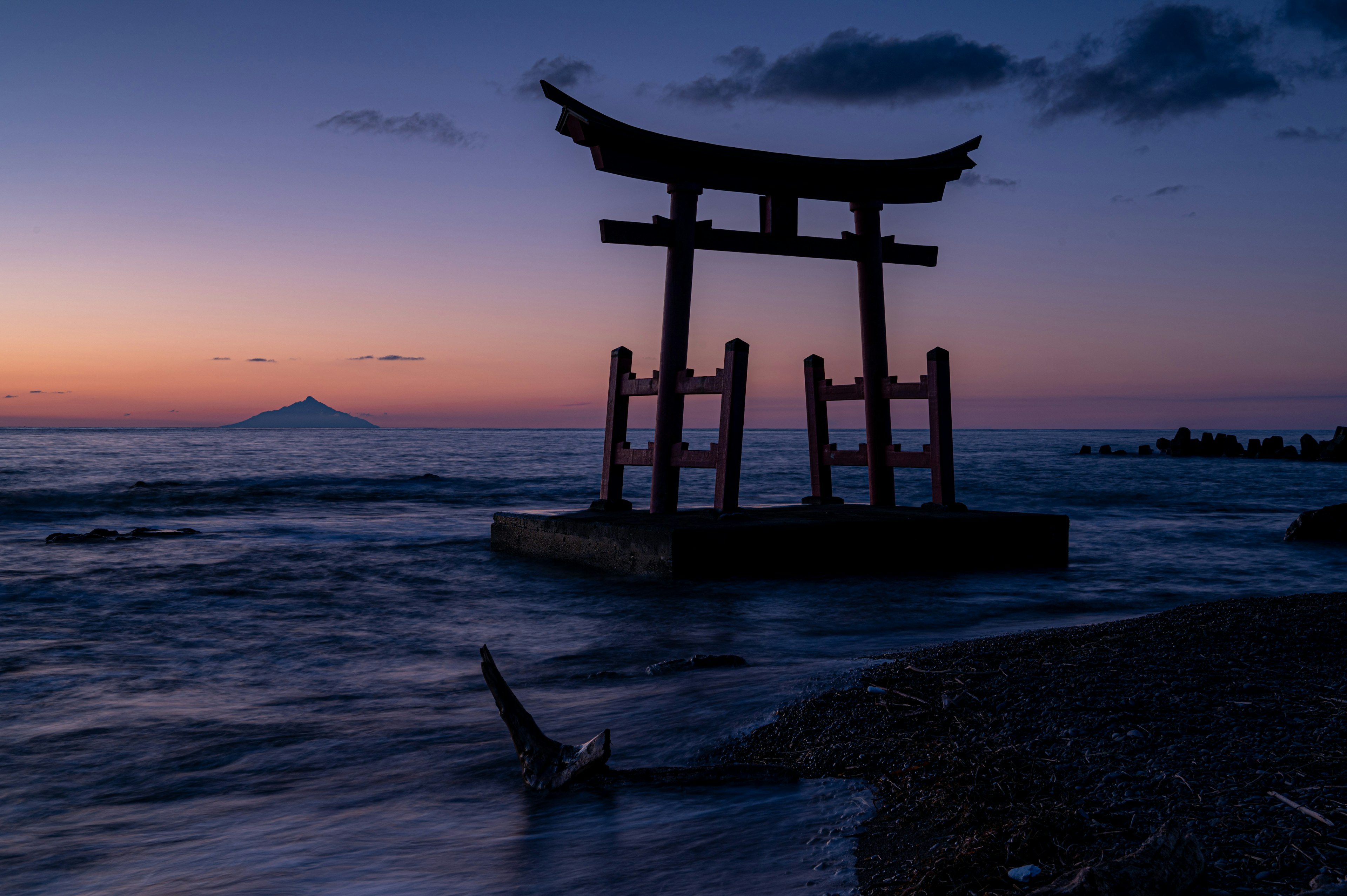 Torii di tepi laut saat matahari terbenam