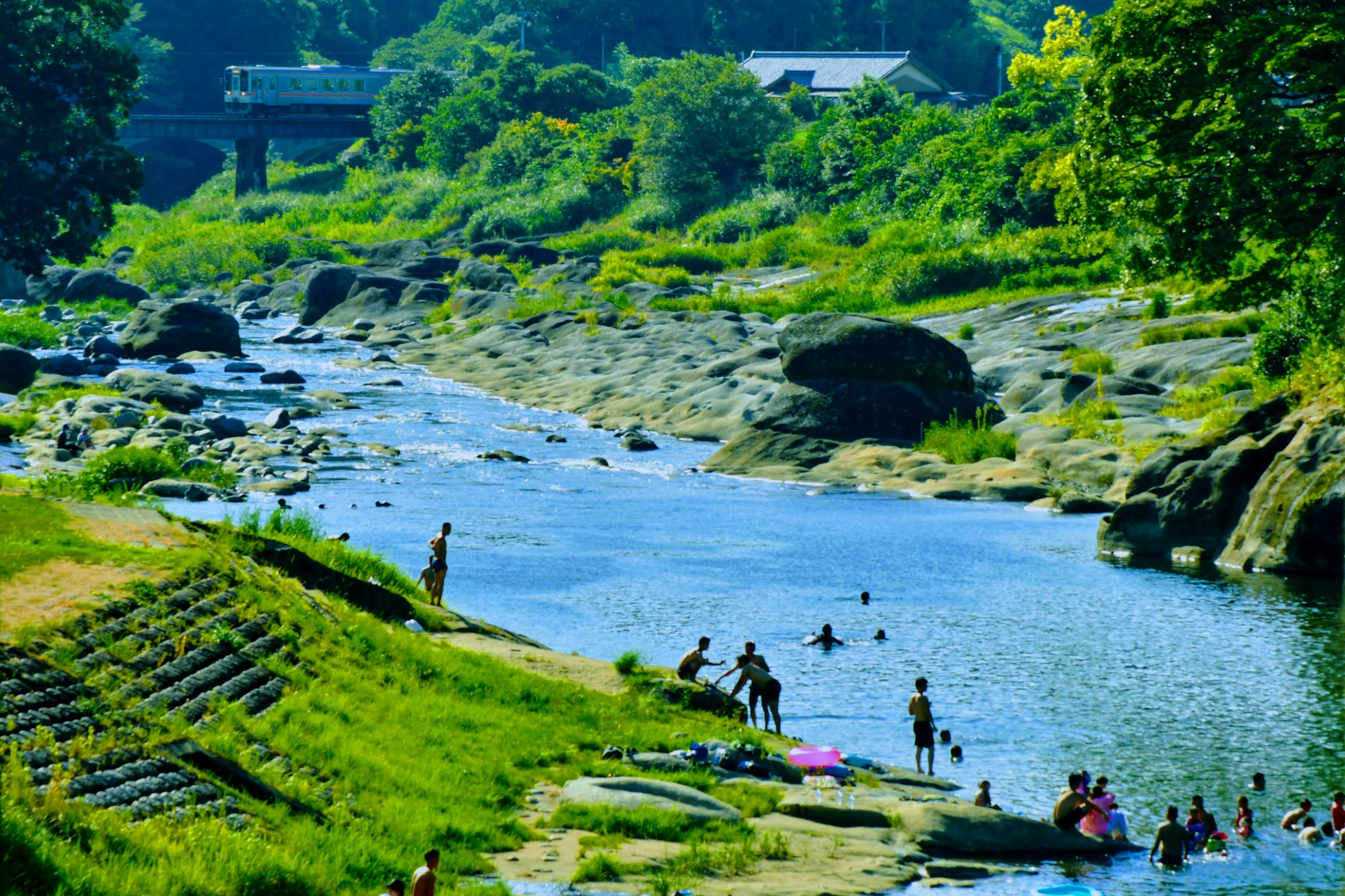 Persone che si godono una giornata di sole vicino a un fiume lussureggiante con rocce