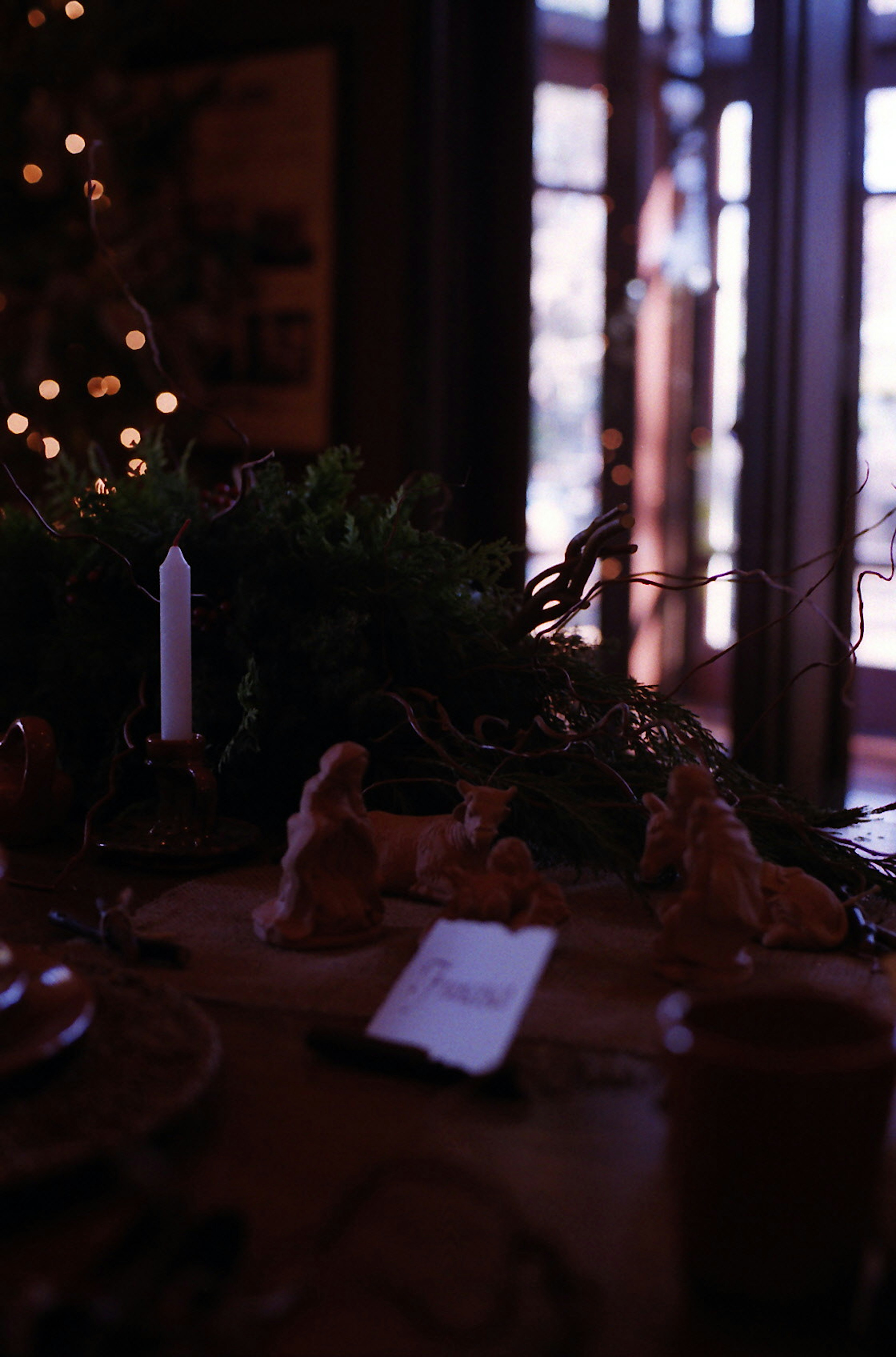 Mise en place de table avec une bougie et des décorations, arbre de Noël en arrière-plan