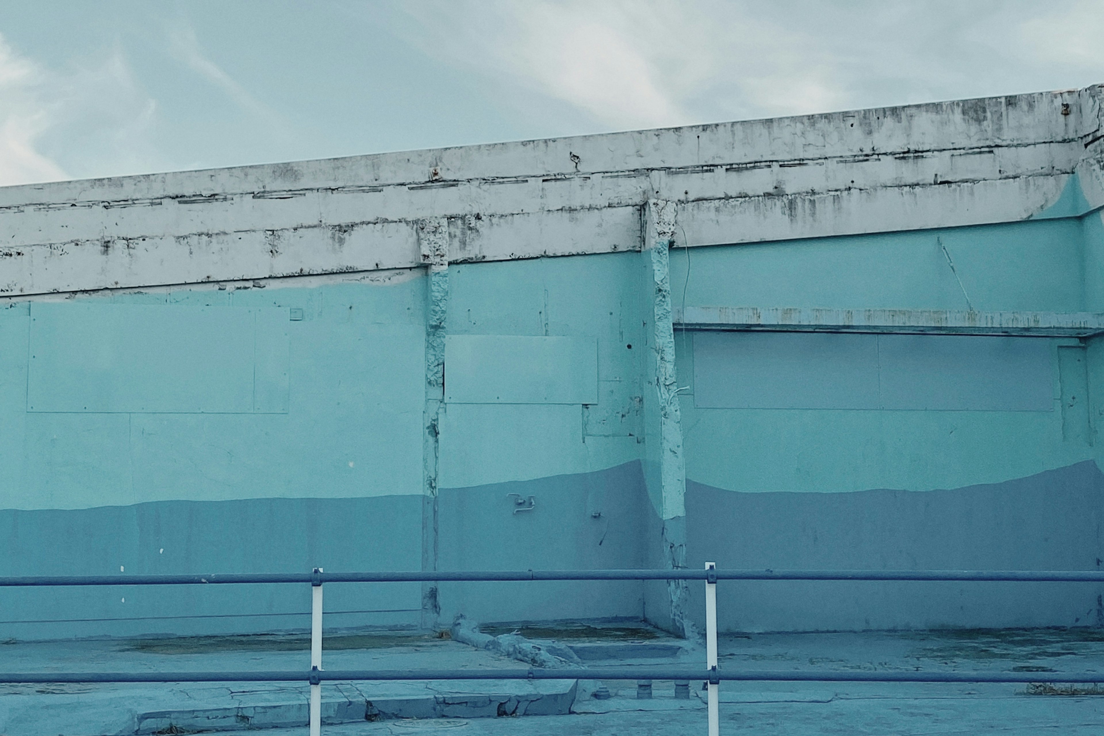 Fond industriel avec des nuances de bleu sur un mur et un ciel nuageux