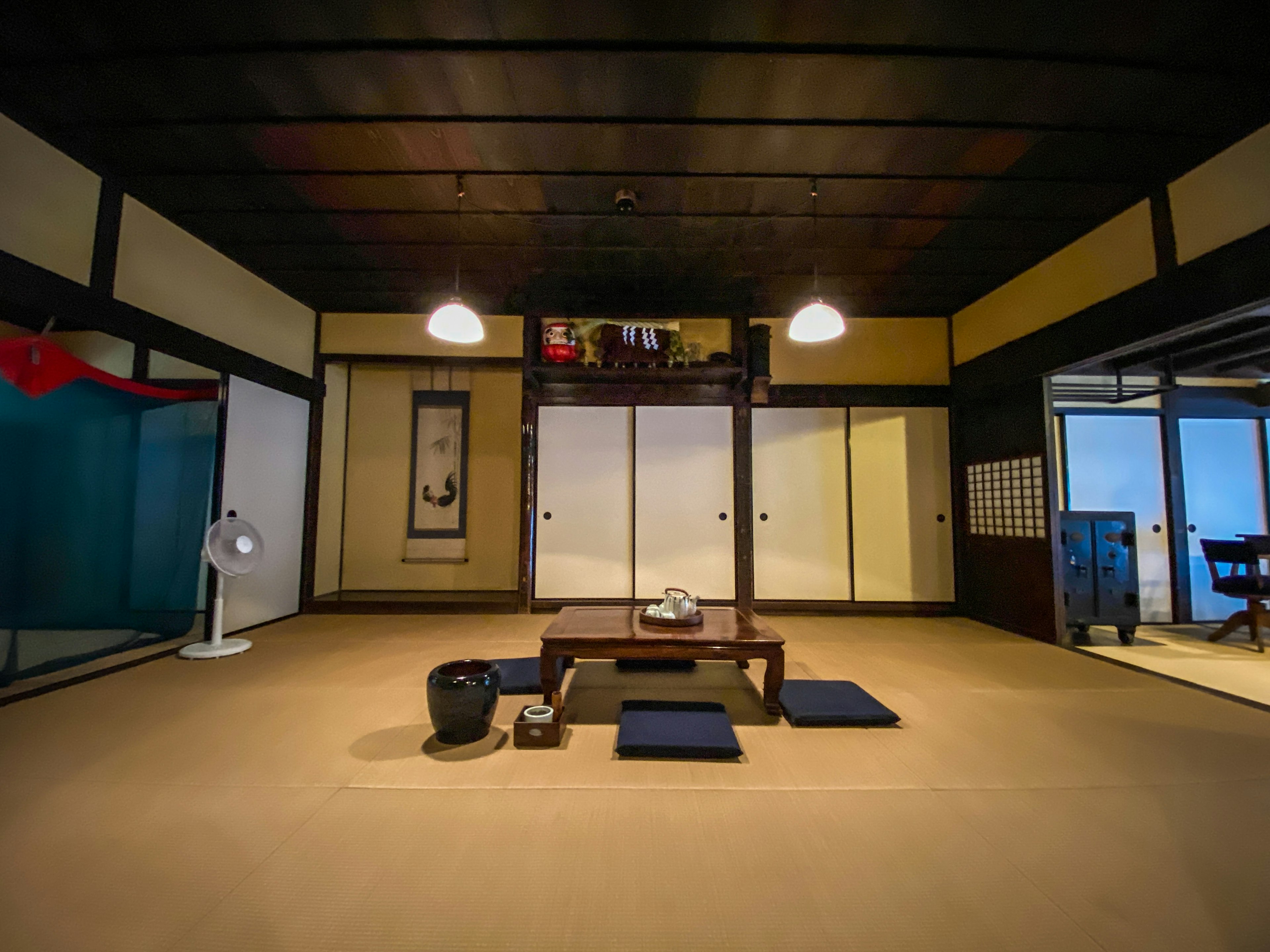 Traditional Japanese interior design featuring tatami flooring, wooden ceiling, low table with cushions, simple lighting, and Japanese decor