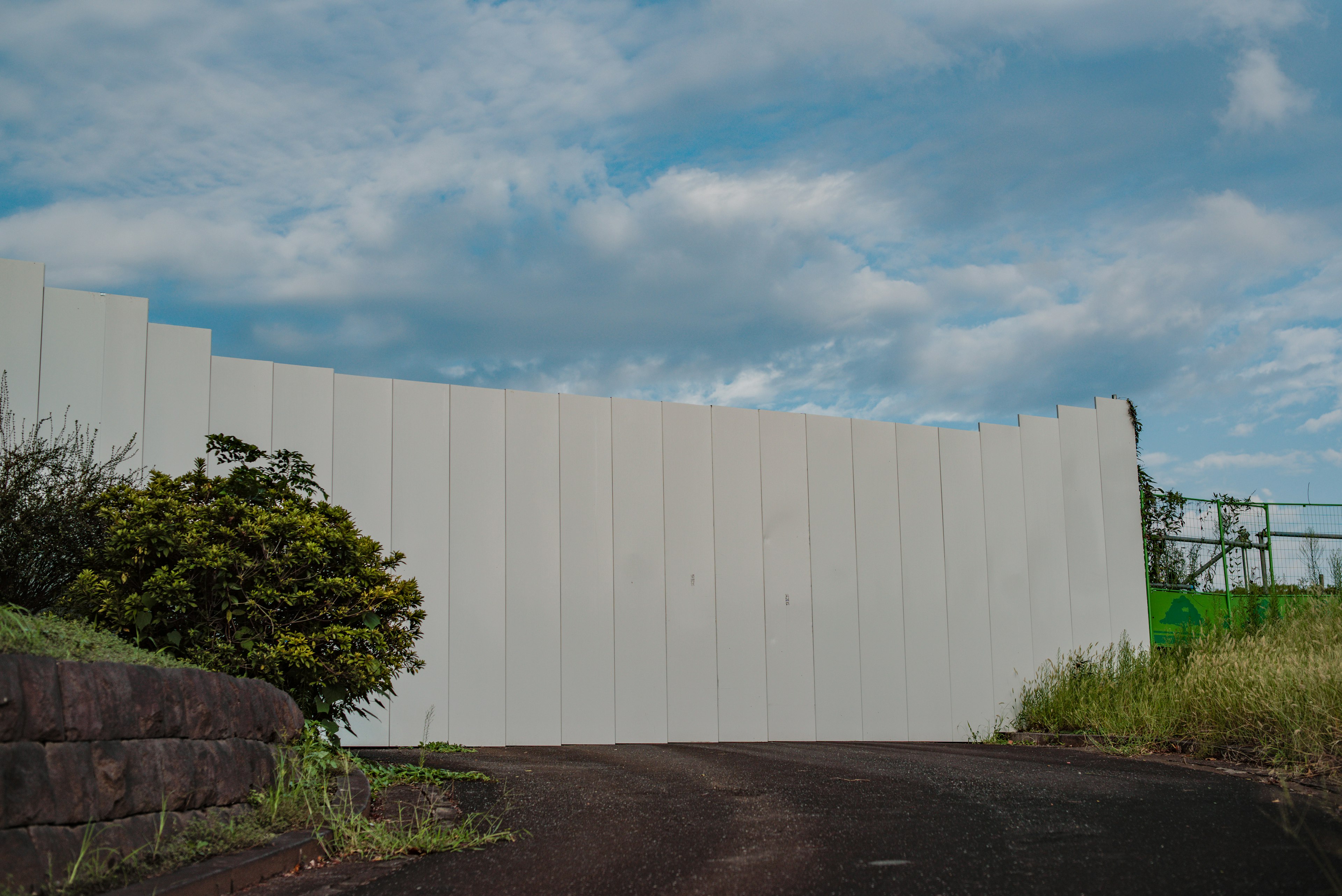 Gebogener weißer Wall vor einem blauen Himmel mit verstreuten Wolken