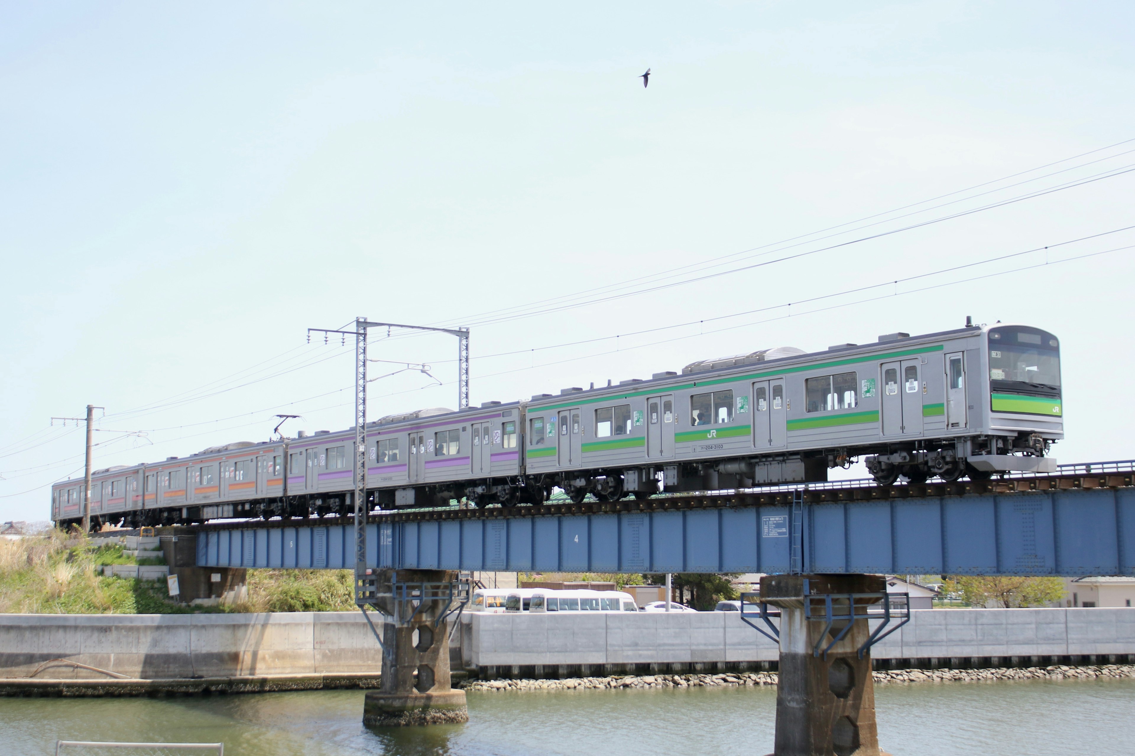 Un treno con una striscia verde che attraversa un ponte sopra l'acqua