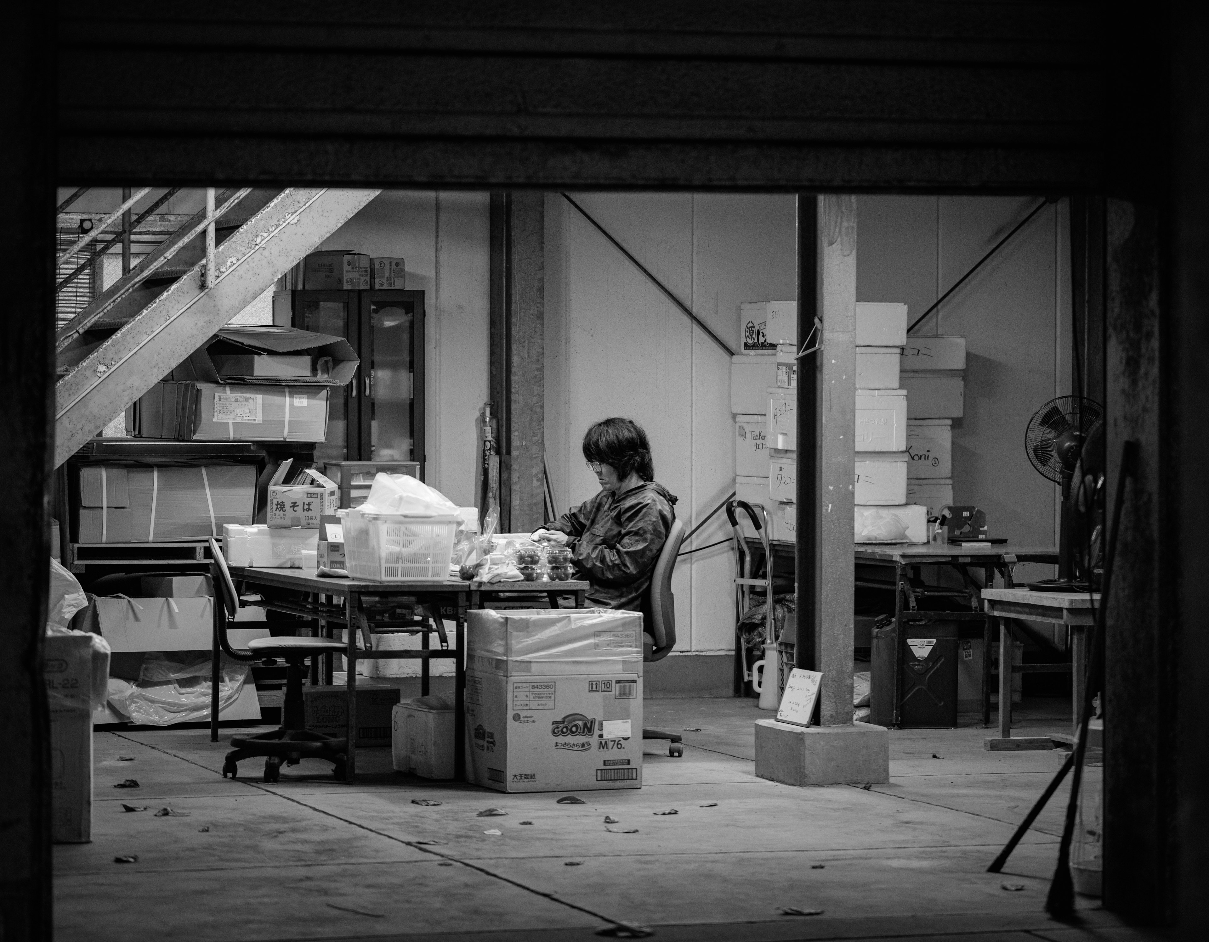 A person sitting in a quiet workspace surrounded by boxes