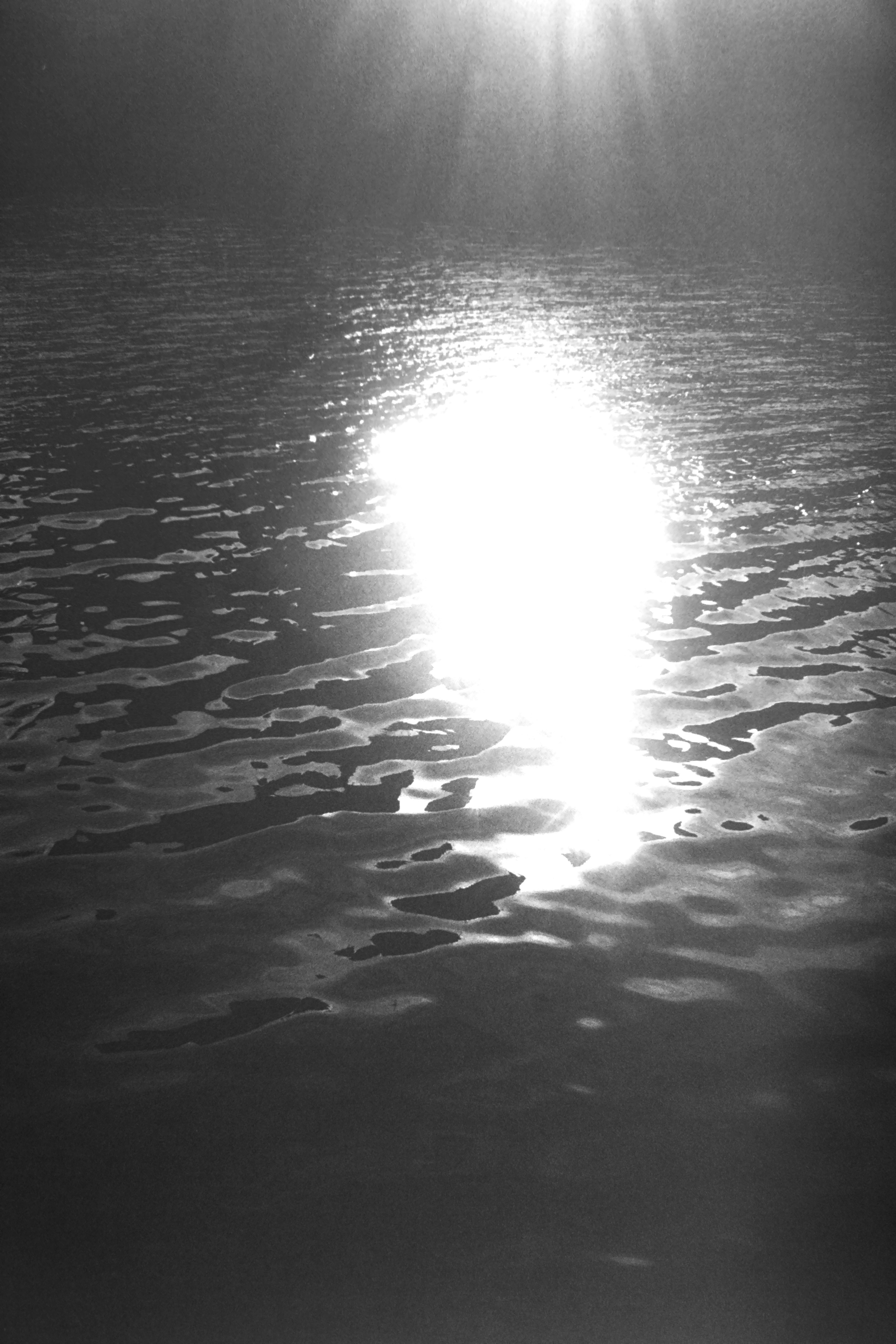 Image en noir et blanc montrant le reflet de la lumière du soleil sur la surface de l'eau