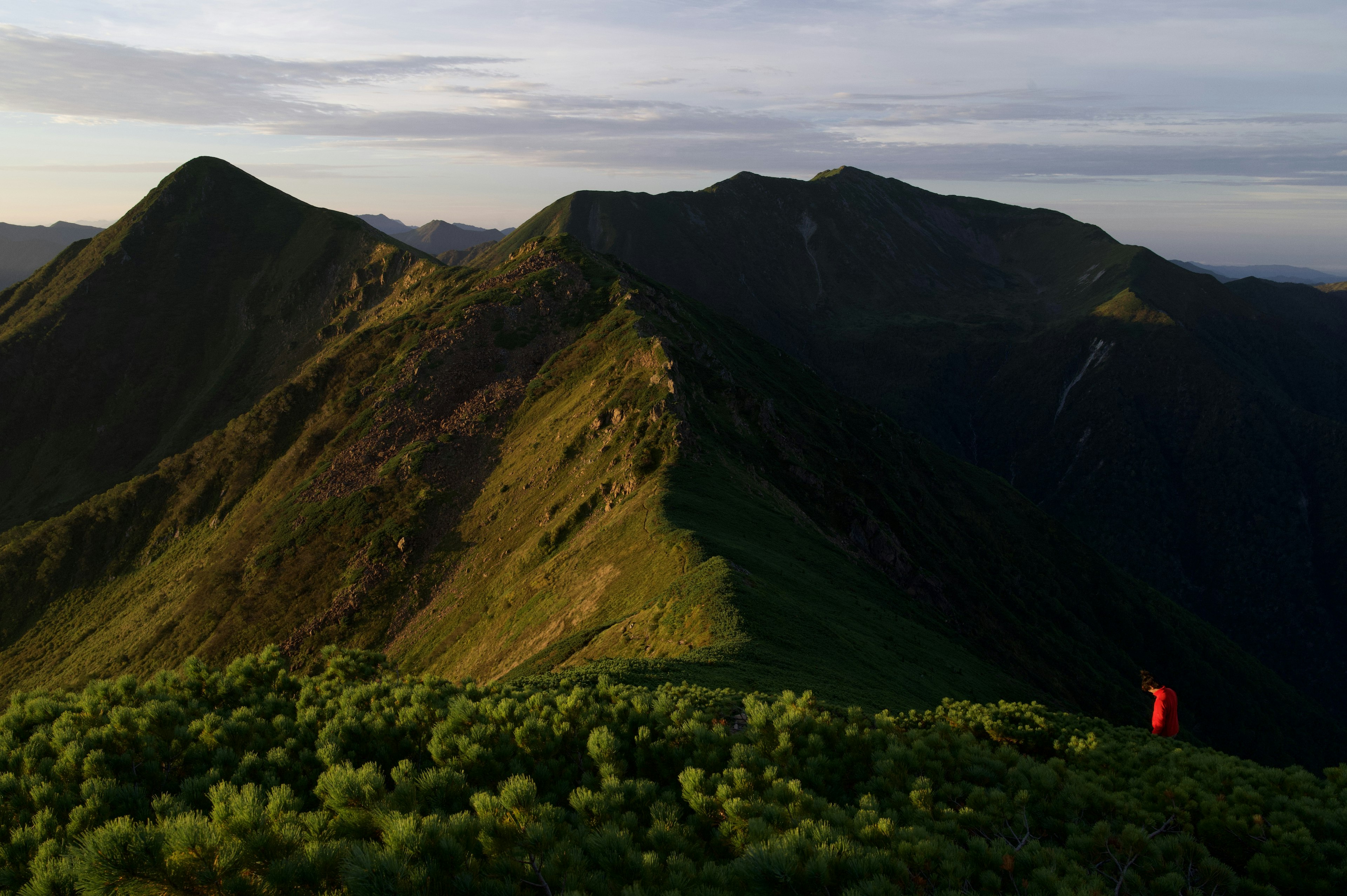 A scenic view of green mountains with a person standing