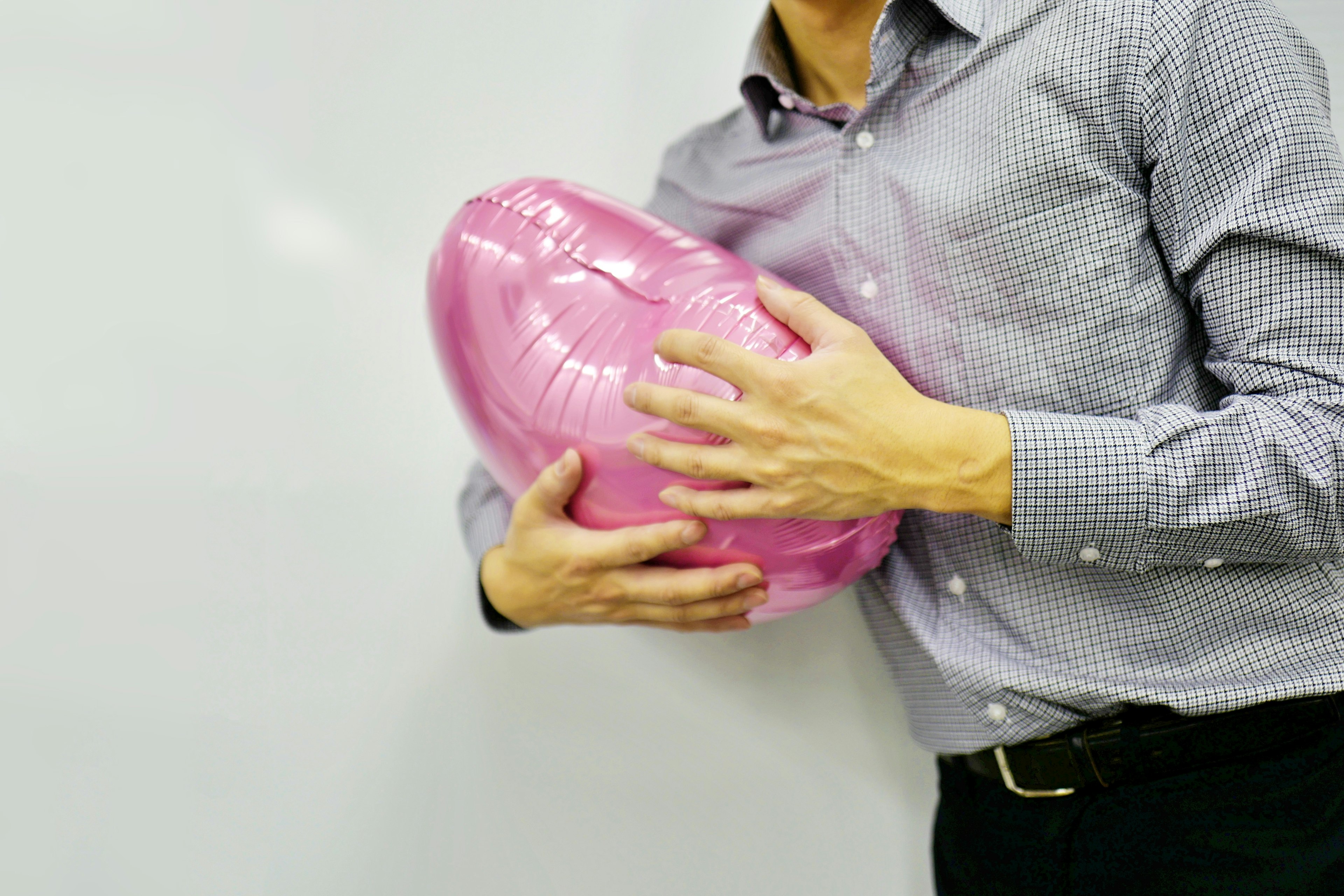 Un hombre sosteniendo un globo rosa en un ambiente casual