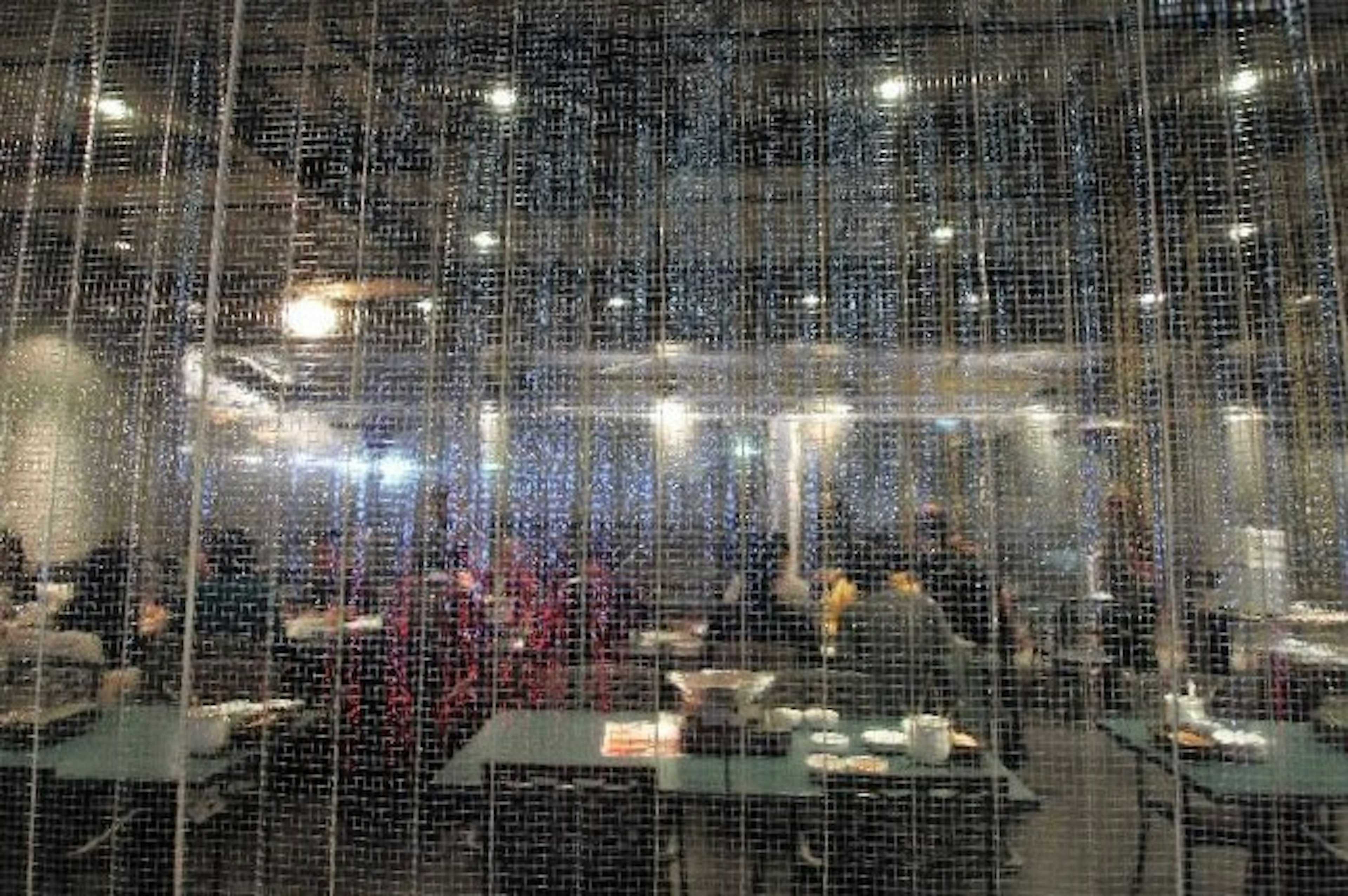 Interior of a restaurant seen through a transparent curtain with diners