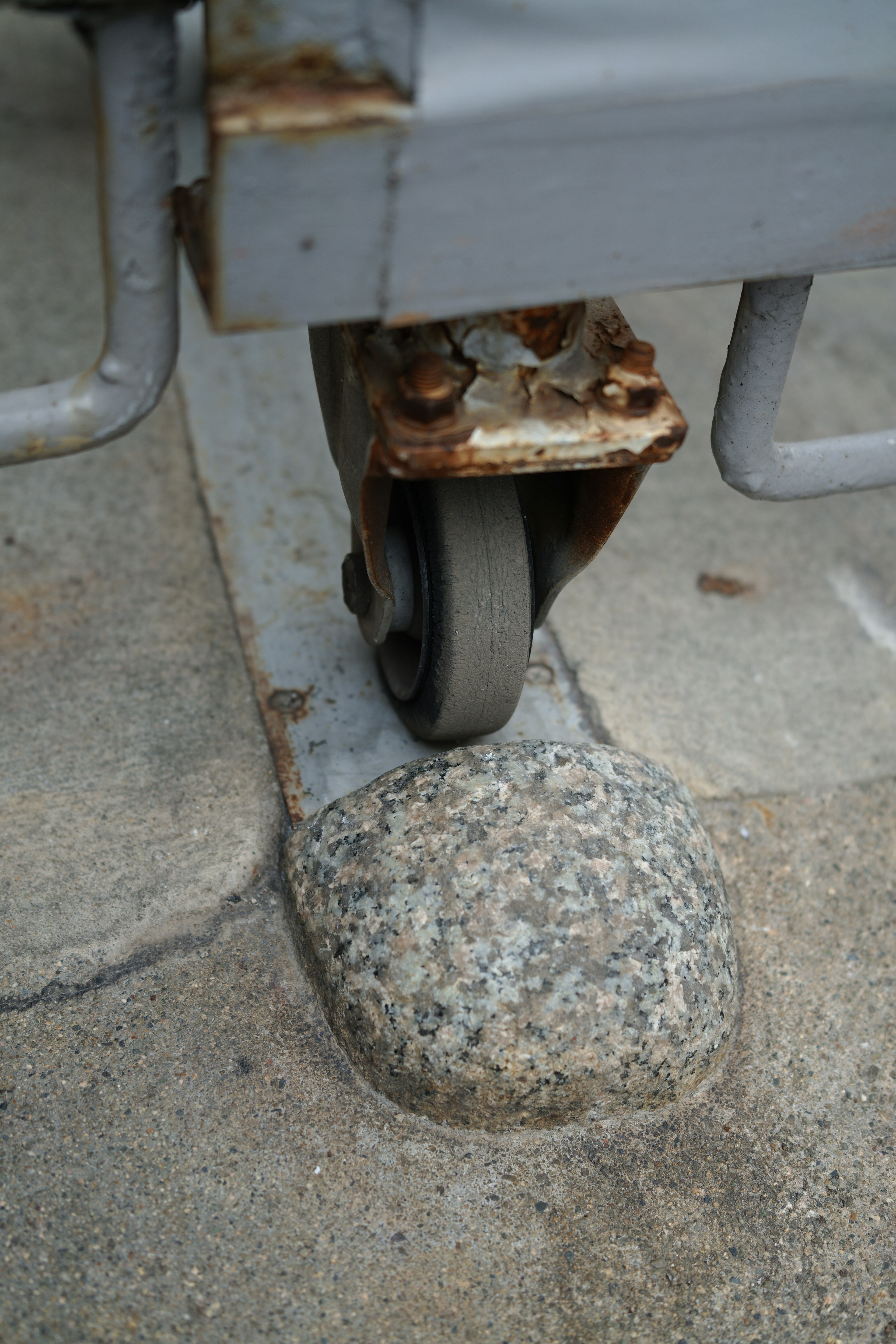 Rusty wheel resting on a stone with a metal frame