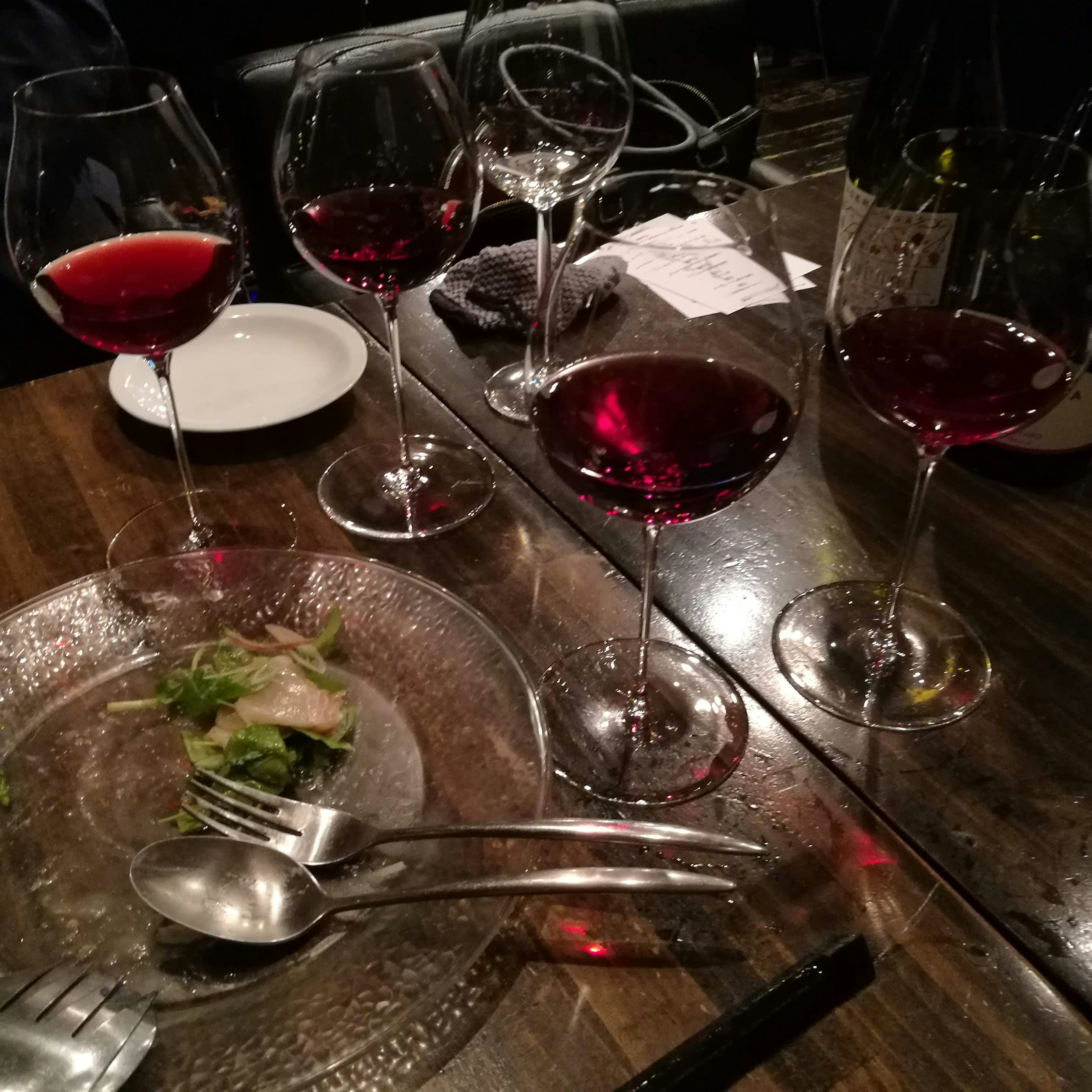 Table avec plusieurs verres de vin rouge et une assiette de salade