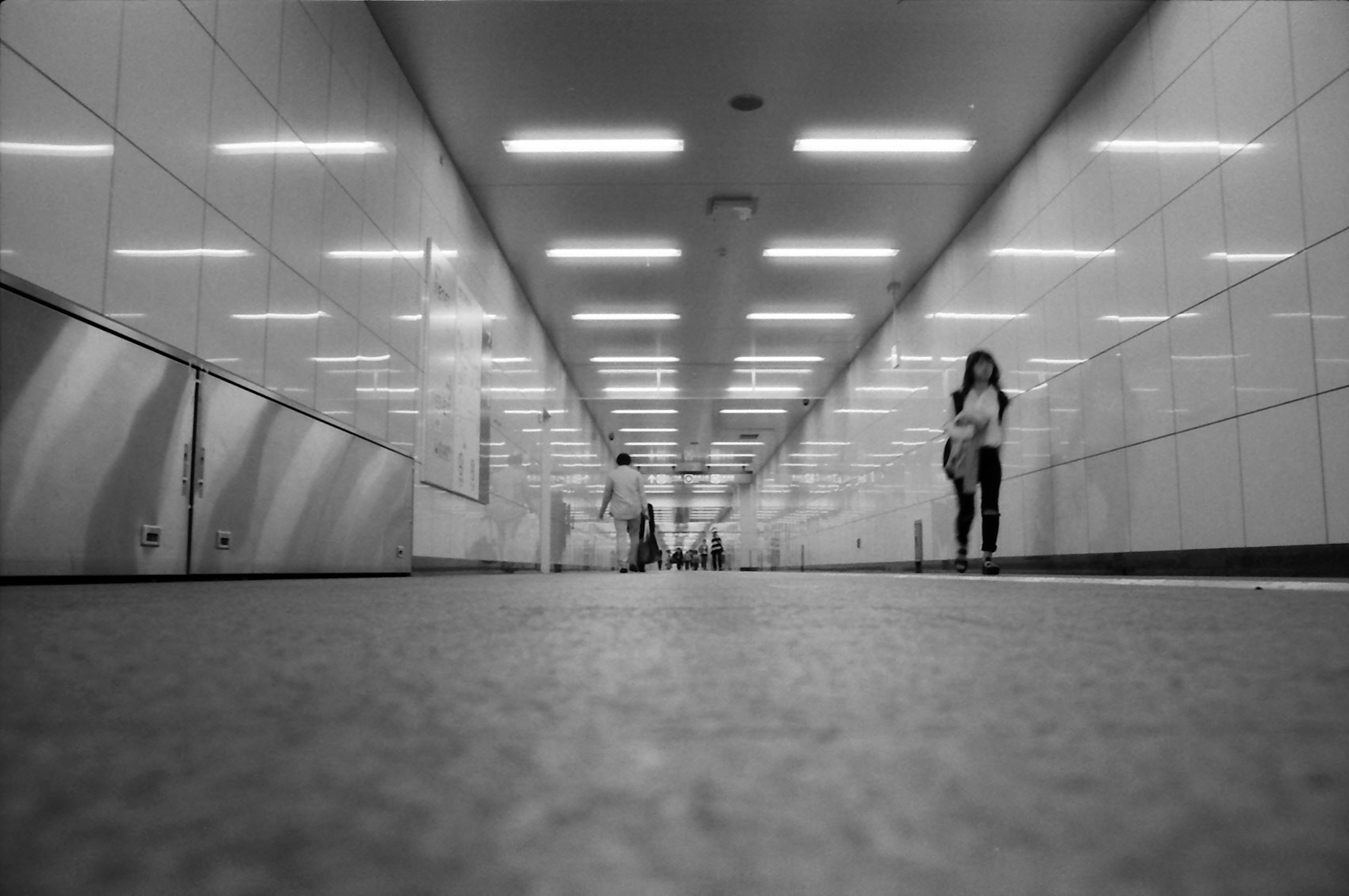 Un pasillo en blanco y negro con personas caminando a lo lejos