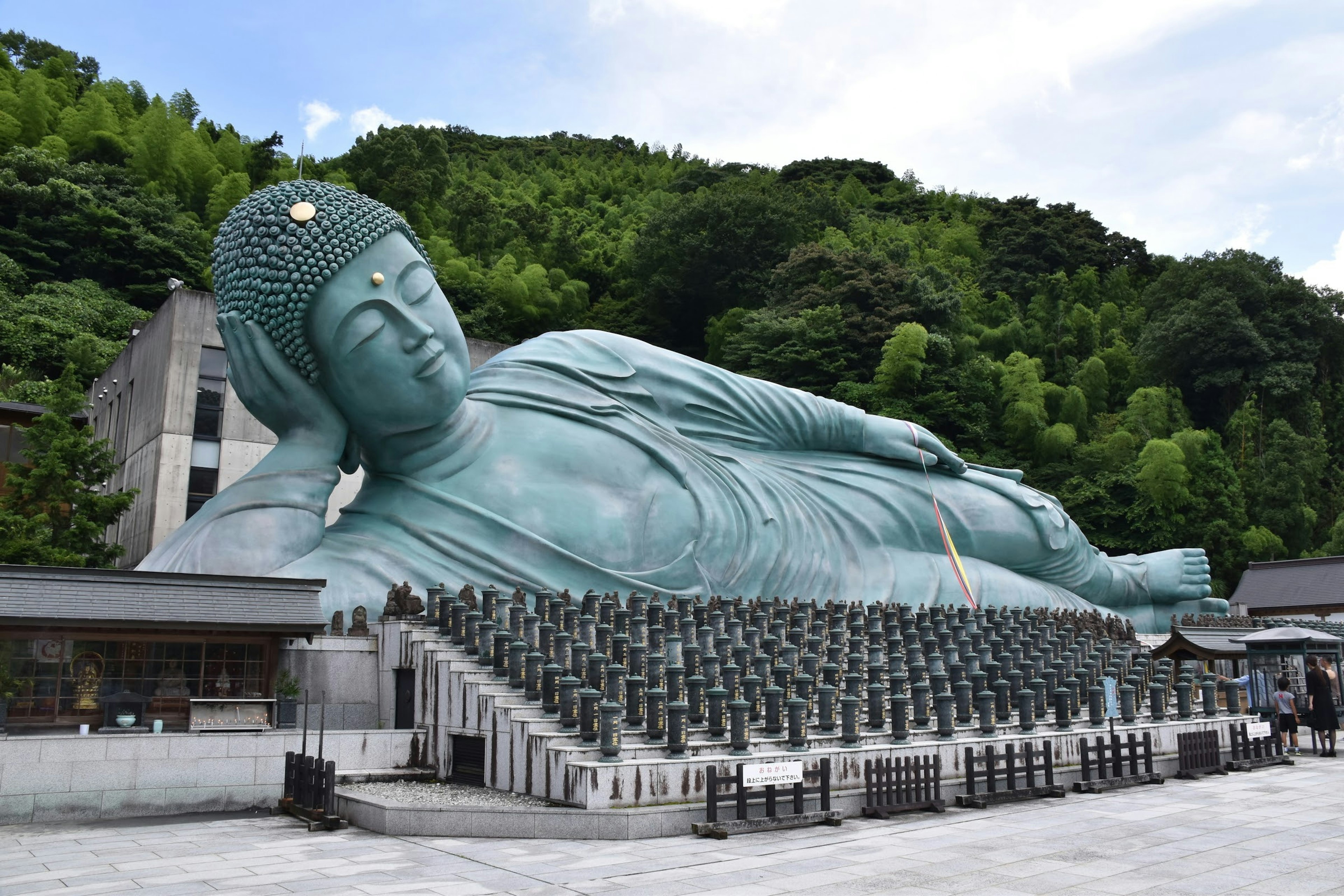 Große liegende Buddha-Statue mit grünen Hügeln im Hintergrund