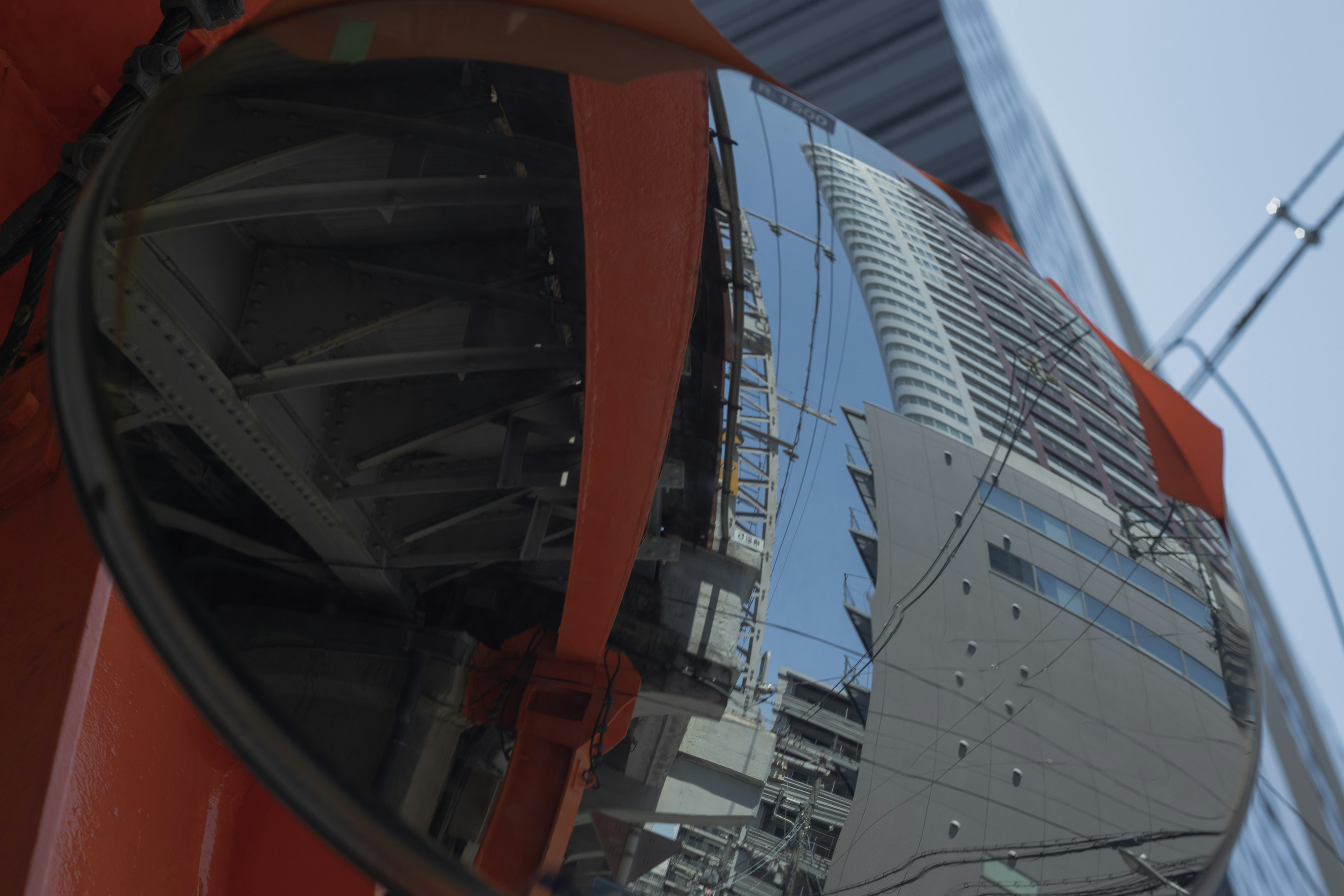 Espejo naranja reflejando edificios urbanos y cielo azul