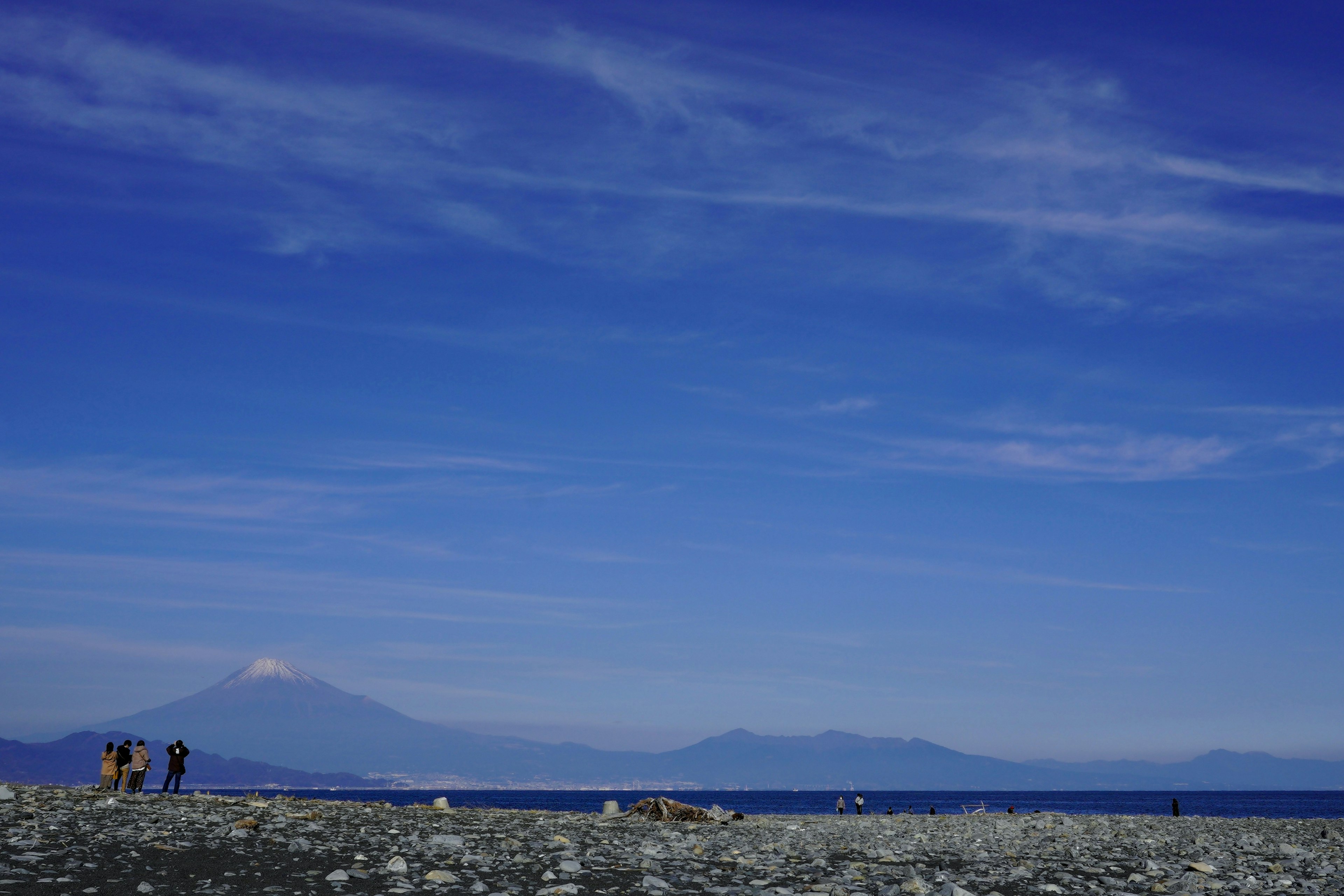 青い空と山々が見える海岸の風景 人々が散歩している