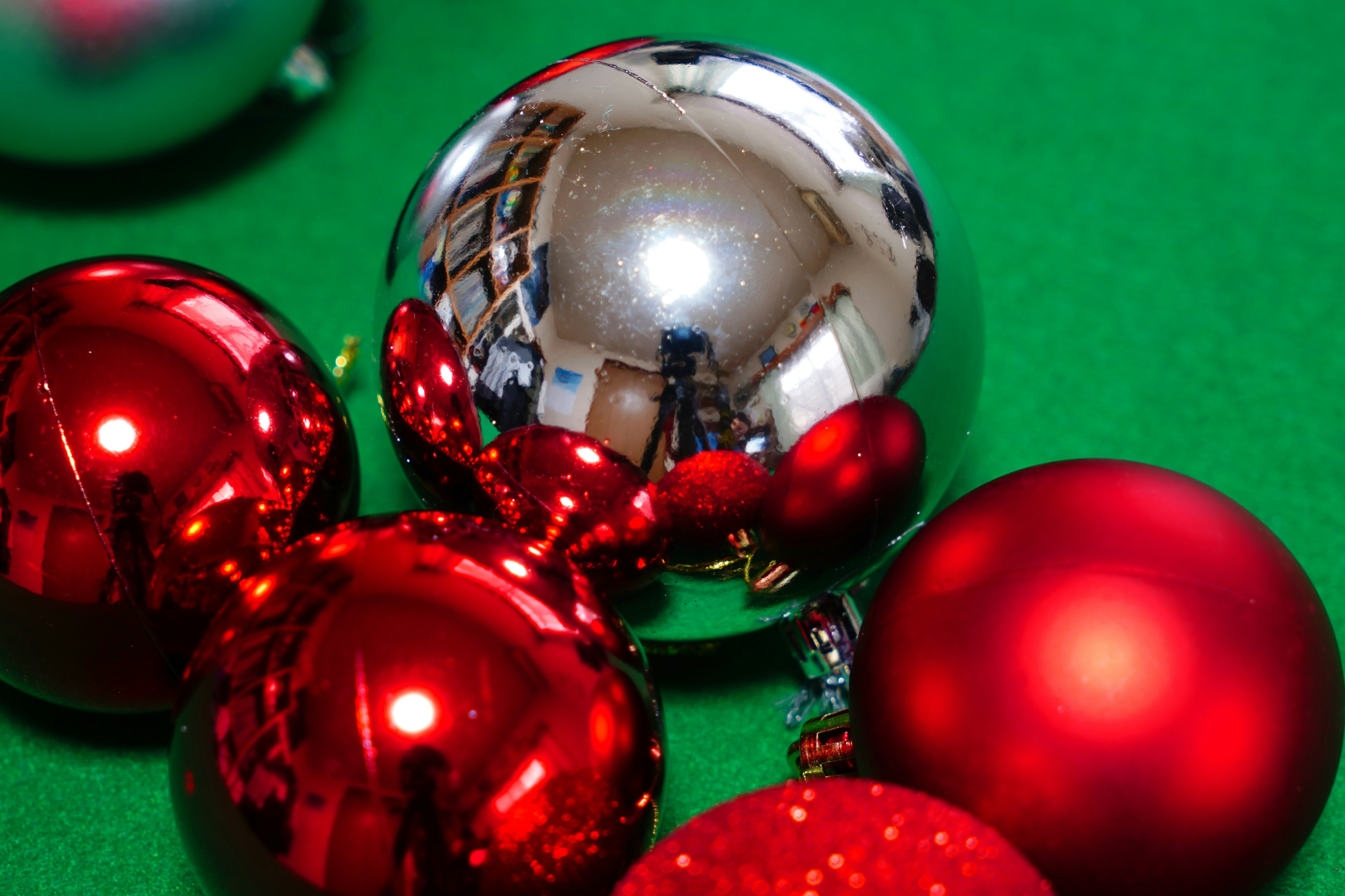 Image featuring red Christmas ornaments and a silver ball on a green background