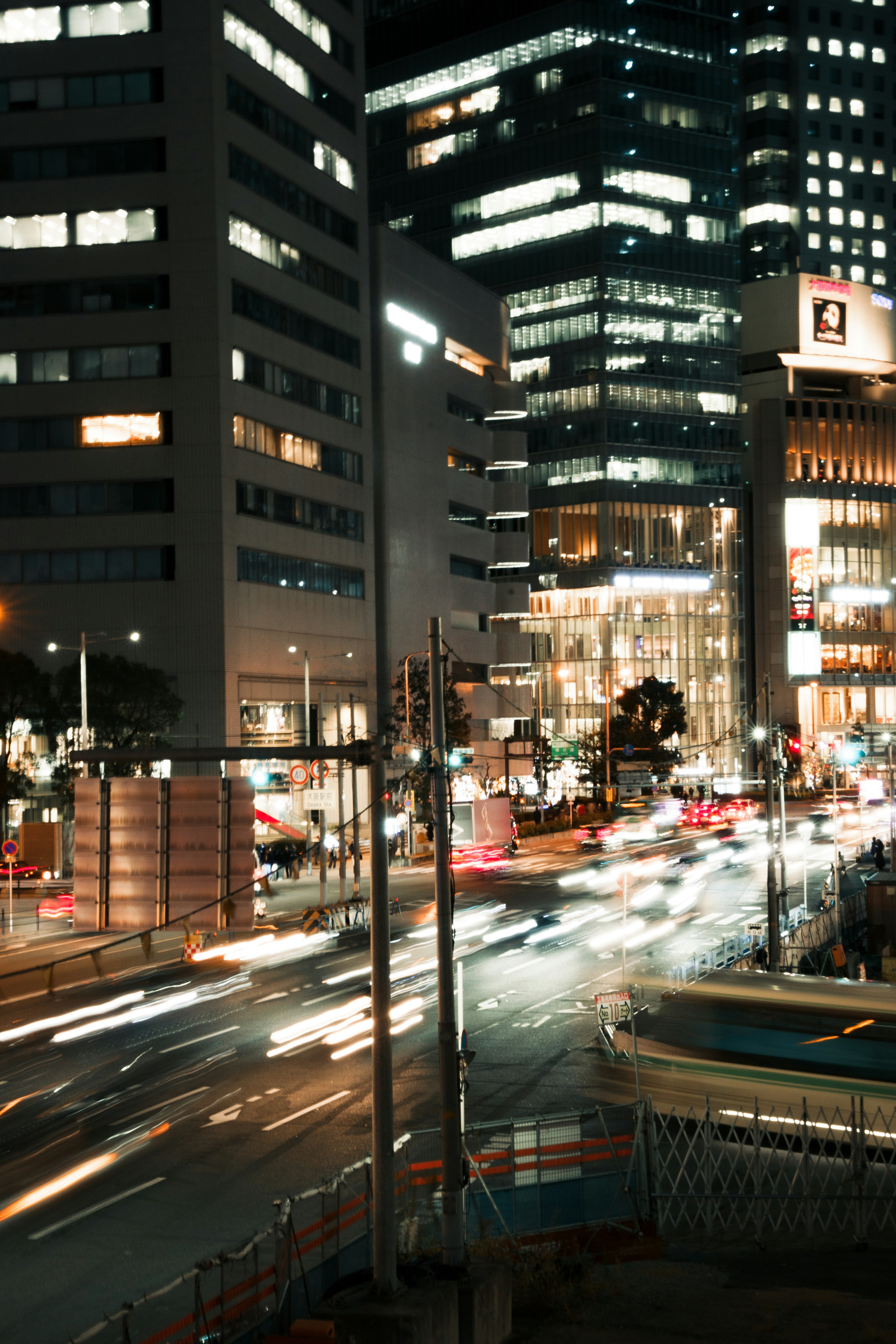 Paesaggio urbano notturno con edifici illuminati e luci di auto in movimento