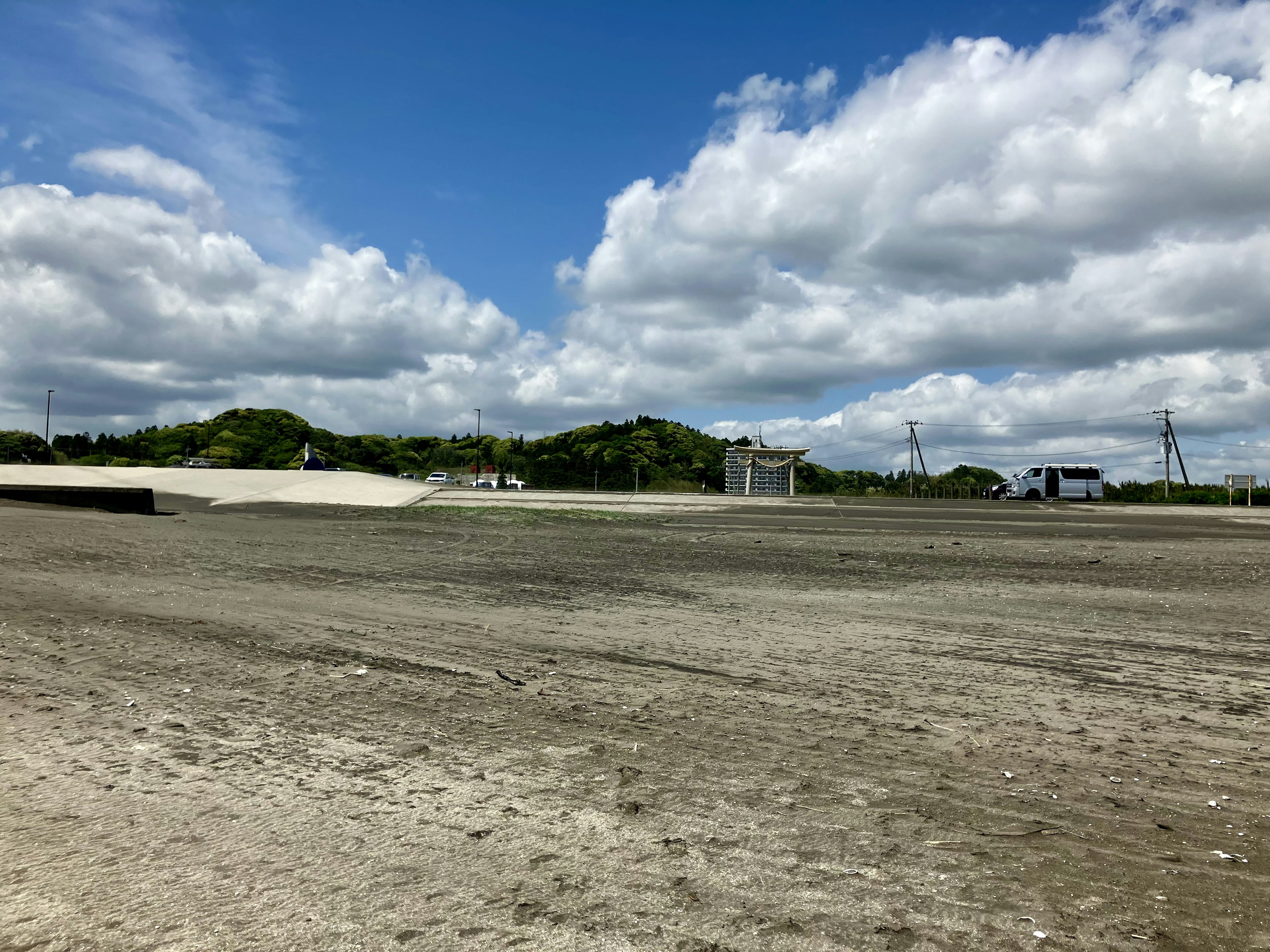 Weite Sandlandschaft unter einem blauen Himmel mit verstreuten Wolken