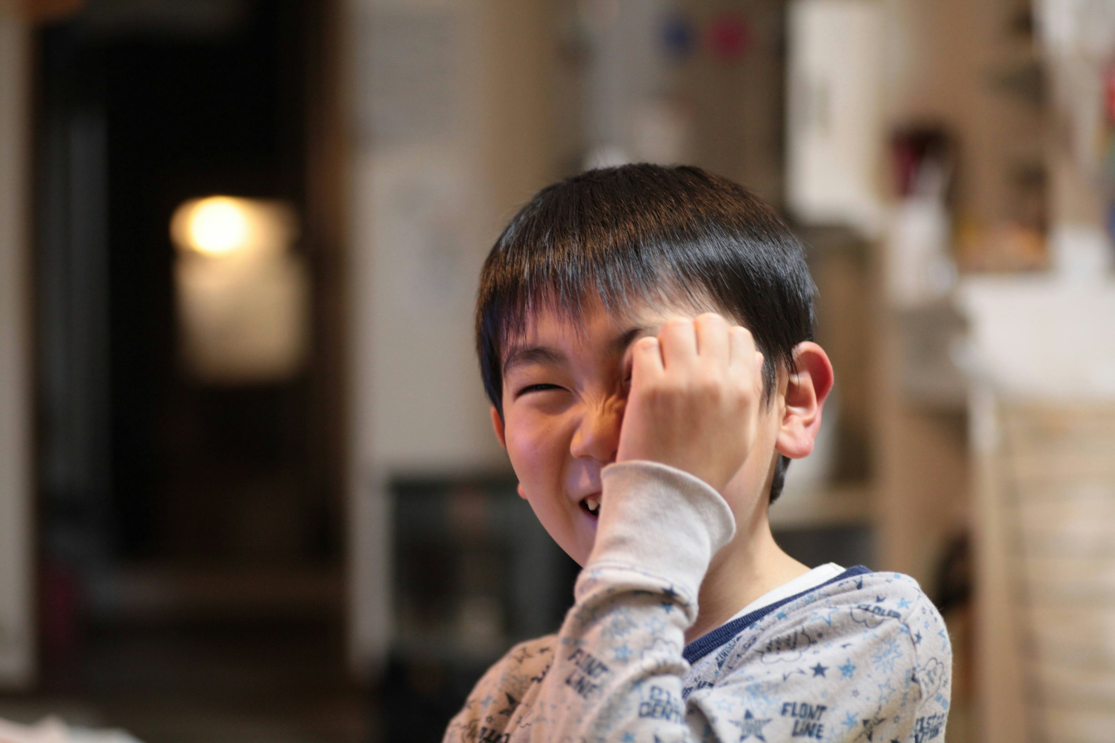 A laughing boy covering one eye with his hand