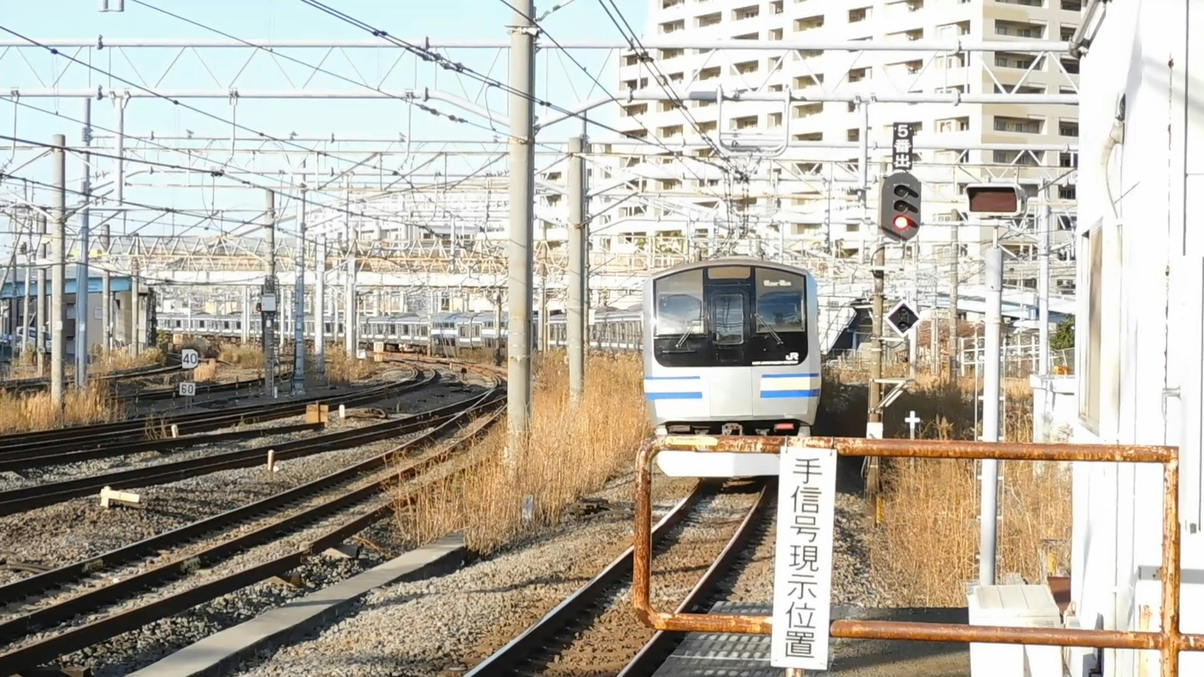 Train approaching on tracks with buildings in the background