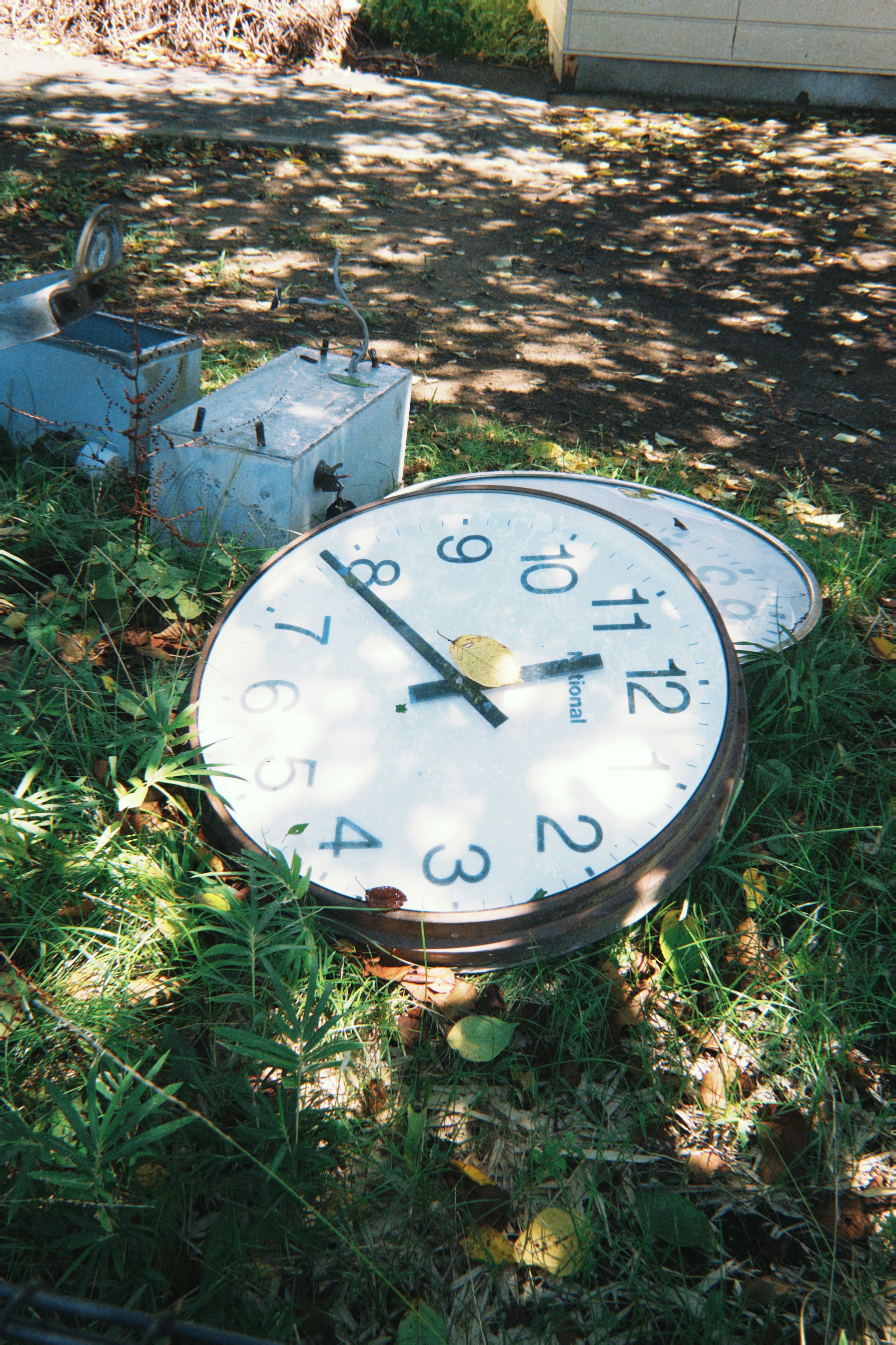 Une horloge cassée posée sur l'herbe