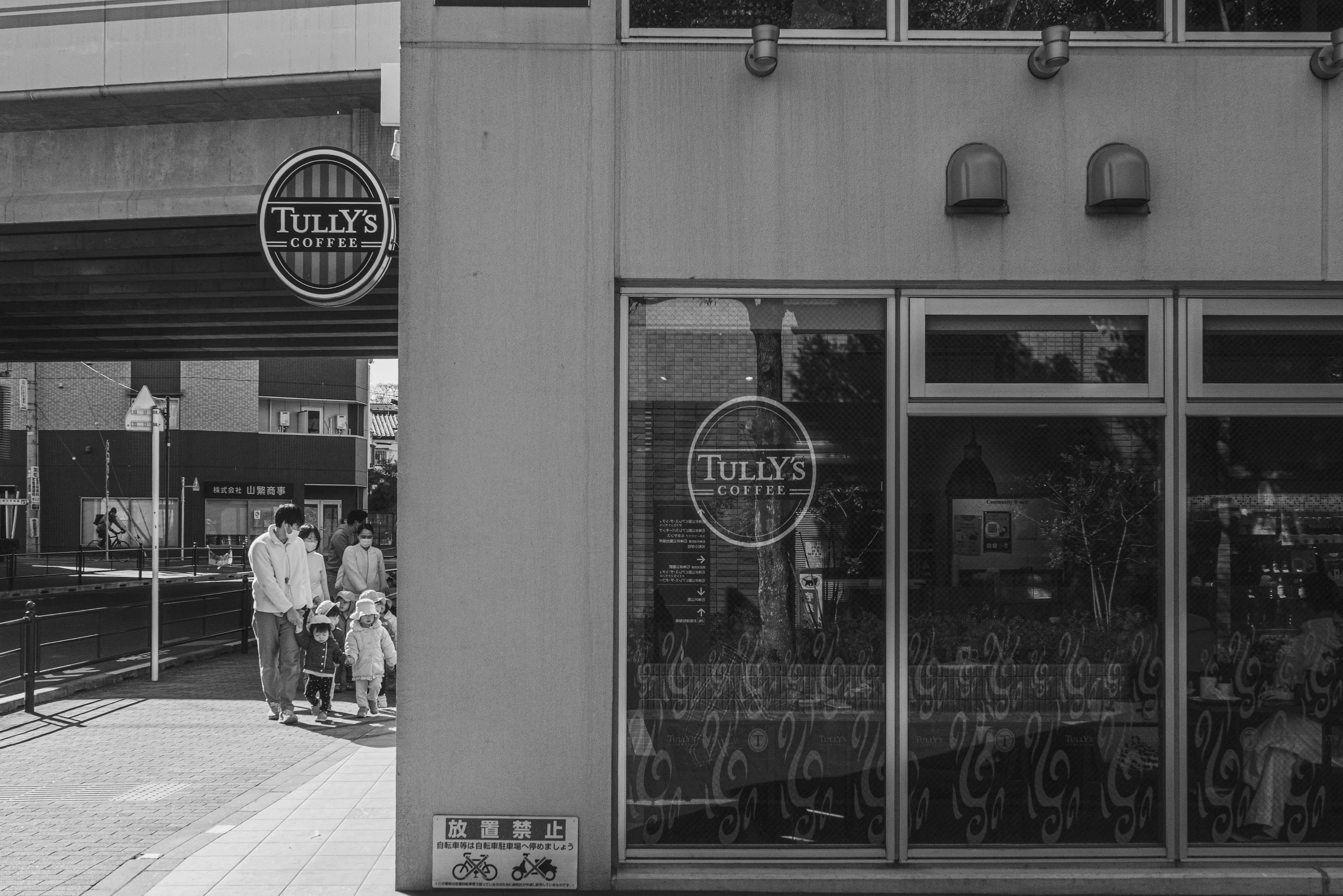 Black and white street scene featuring a cafe exterior and pedestrians