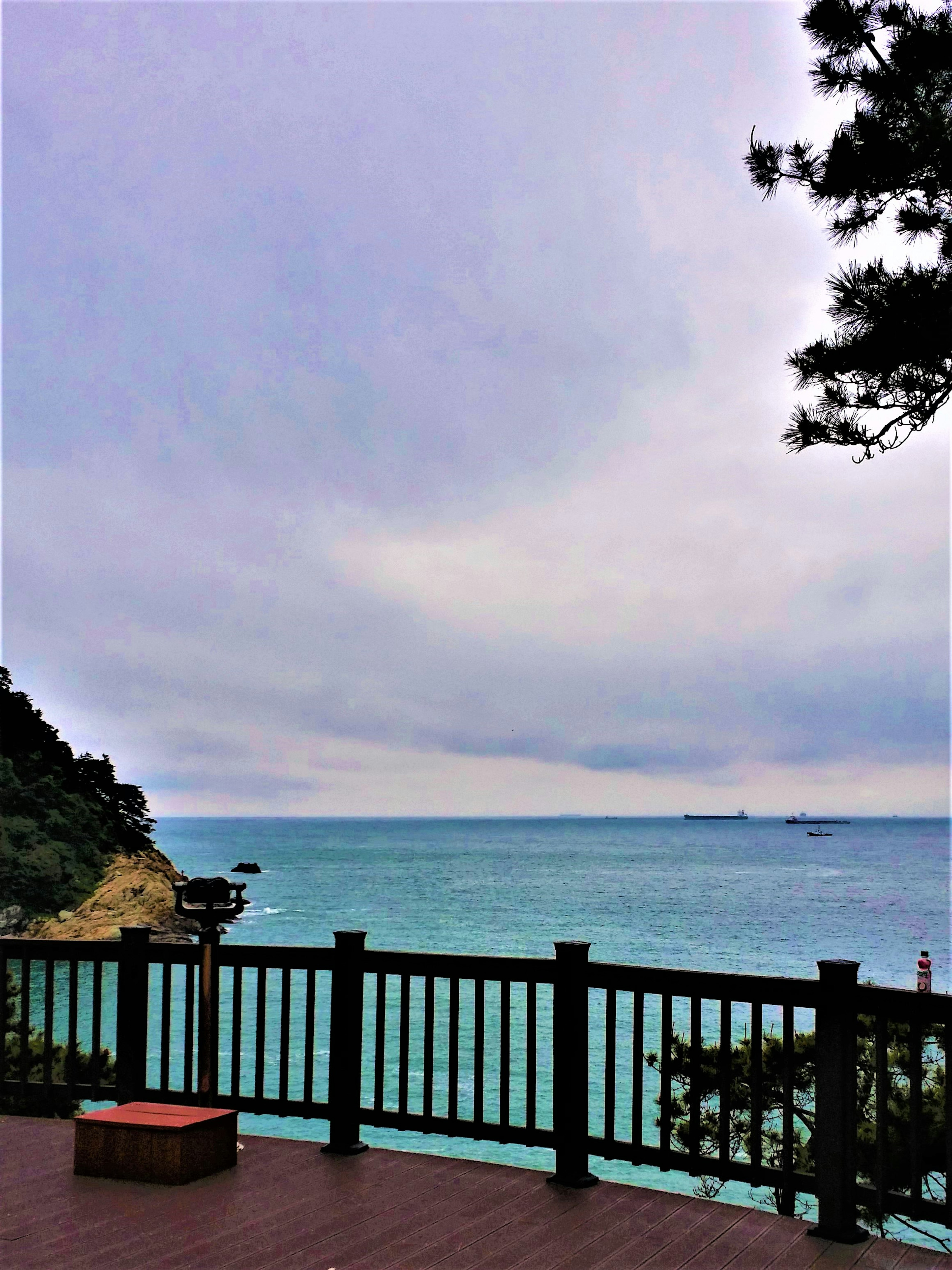 Malerscher Blick auf das ruhige Meer und den bewölkten Himmel von einem Holzdeck