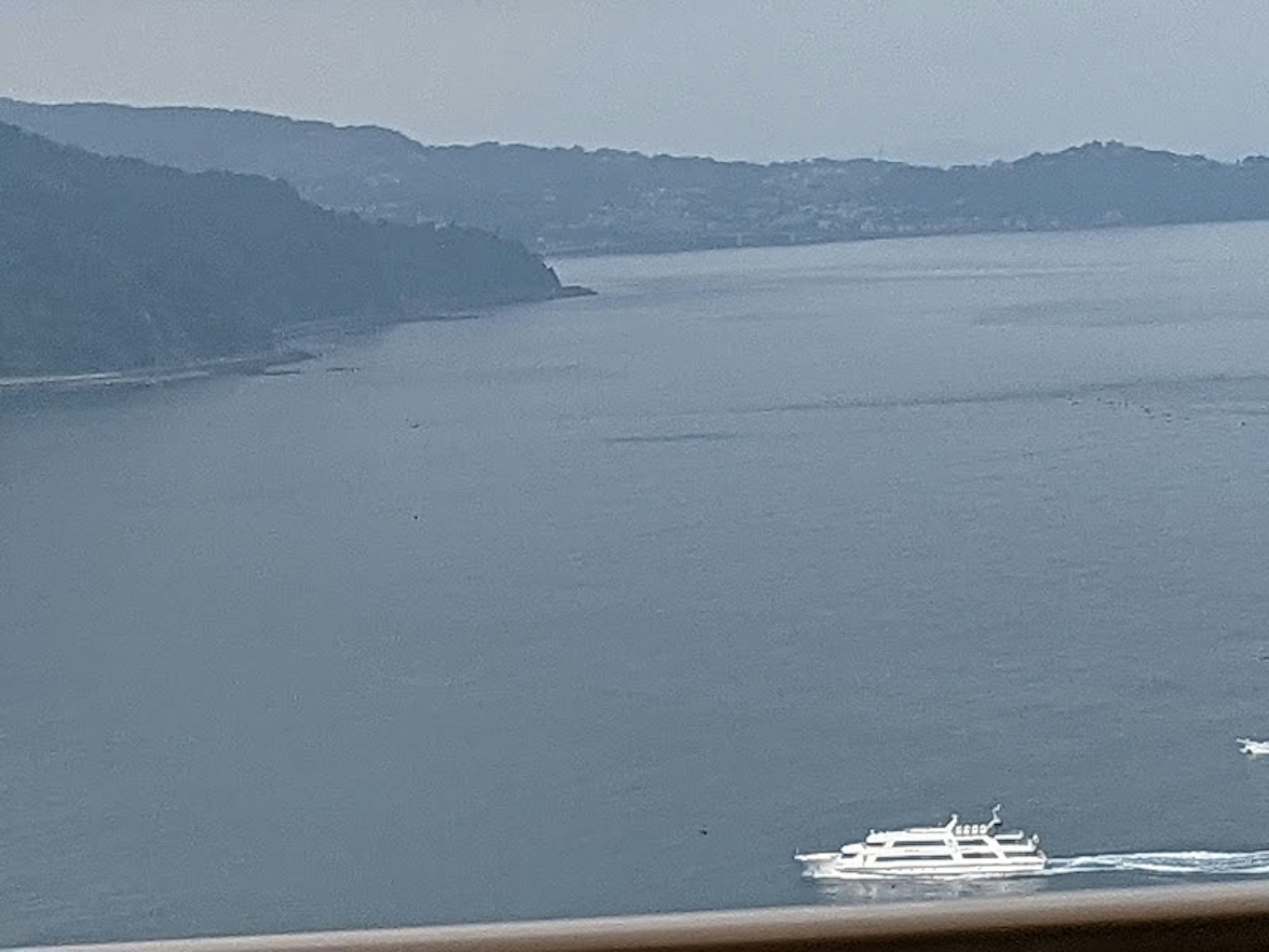 Vista panoramica di montagne e mare calmo con uno yacht bianco