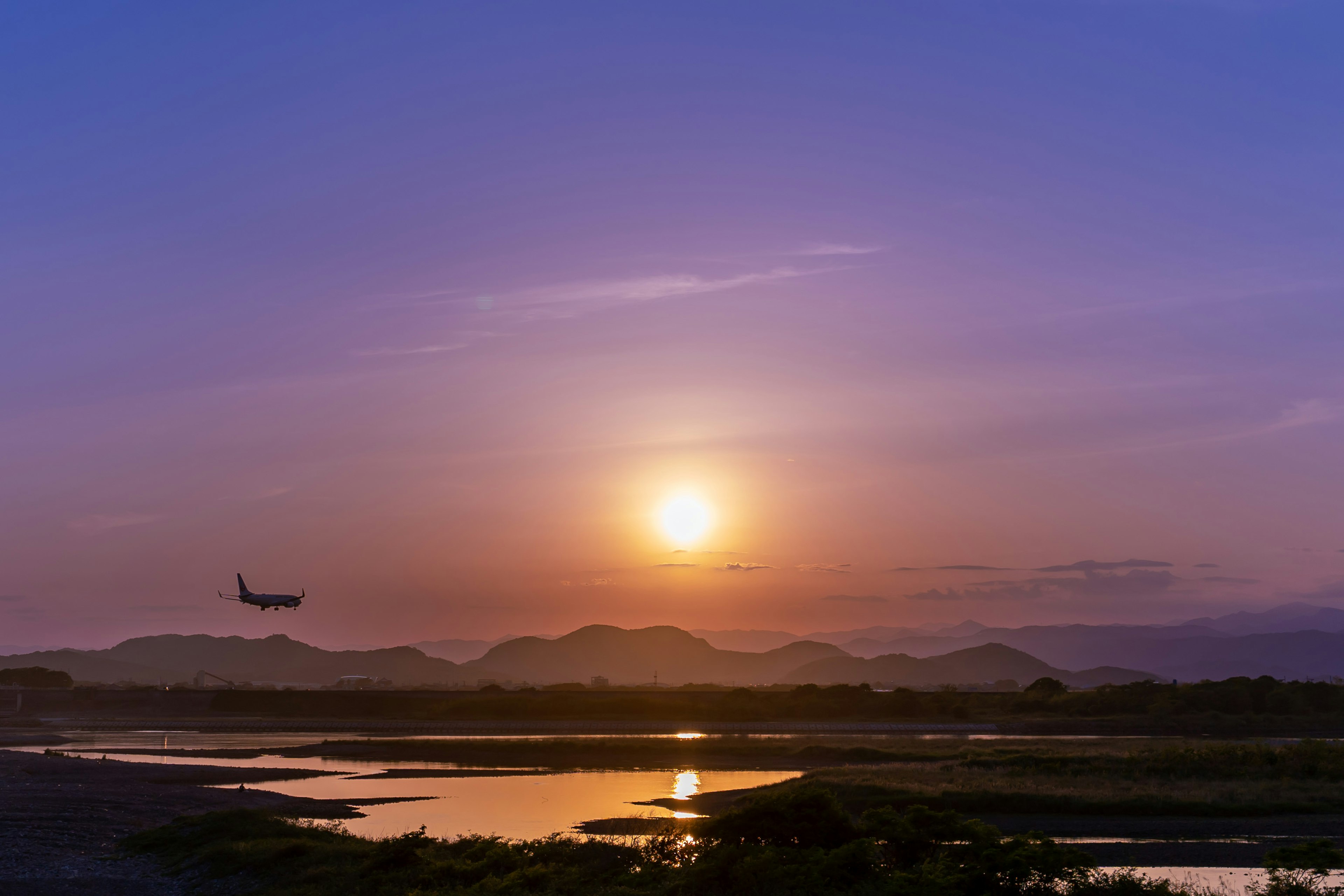 夕日を背景に飛行機が飛ぶ美しい風景