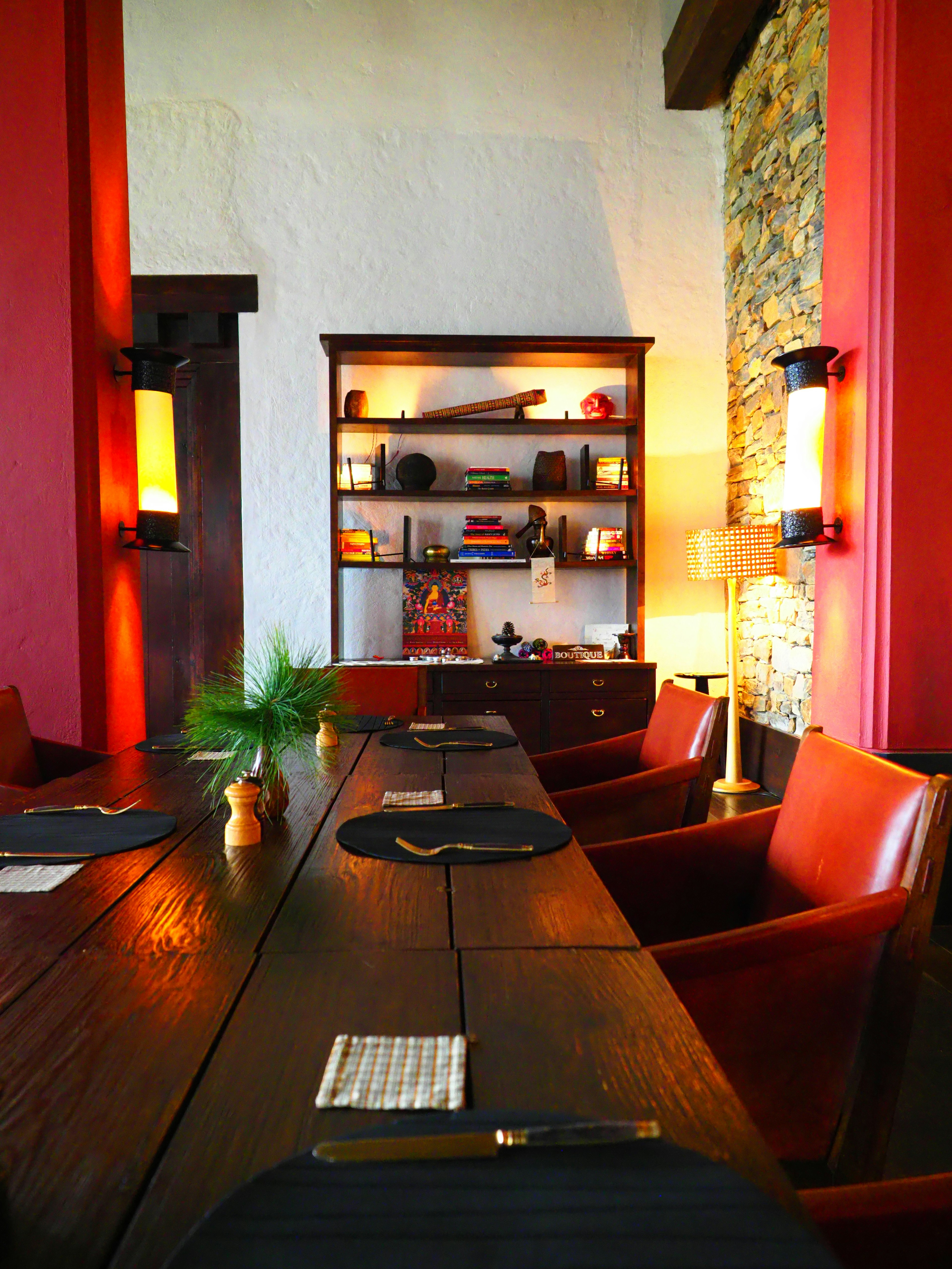 Interior of a restaurant featuring red walls and stone accents Large wooden table with leather chairs