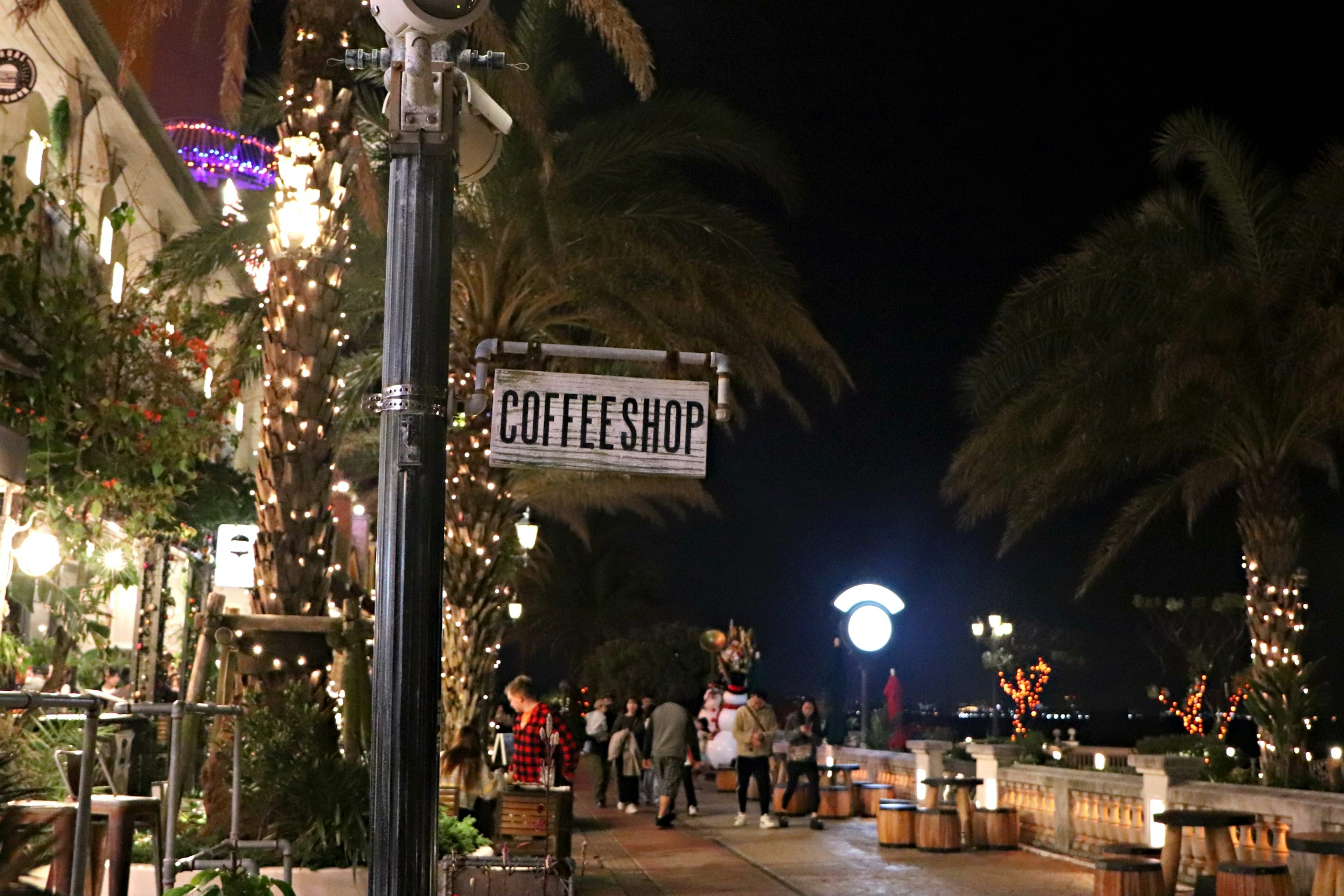 Scena notturna con insegna di caffè e persone che passeggiano