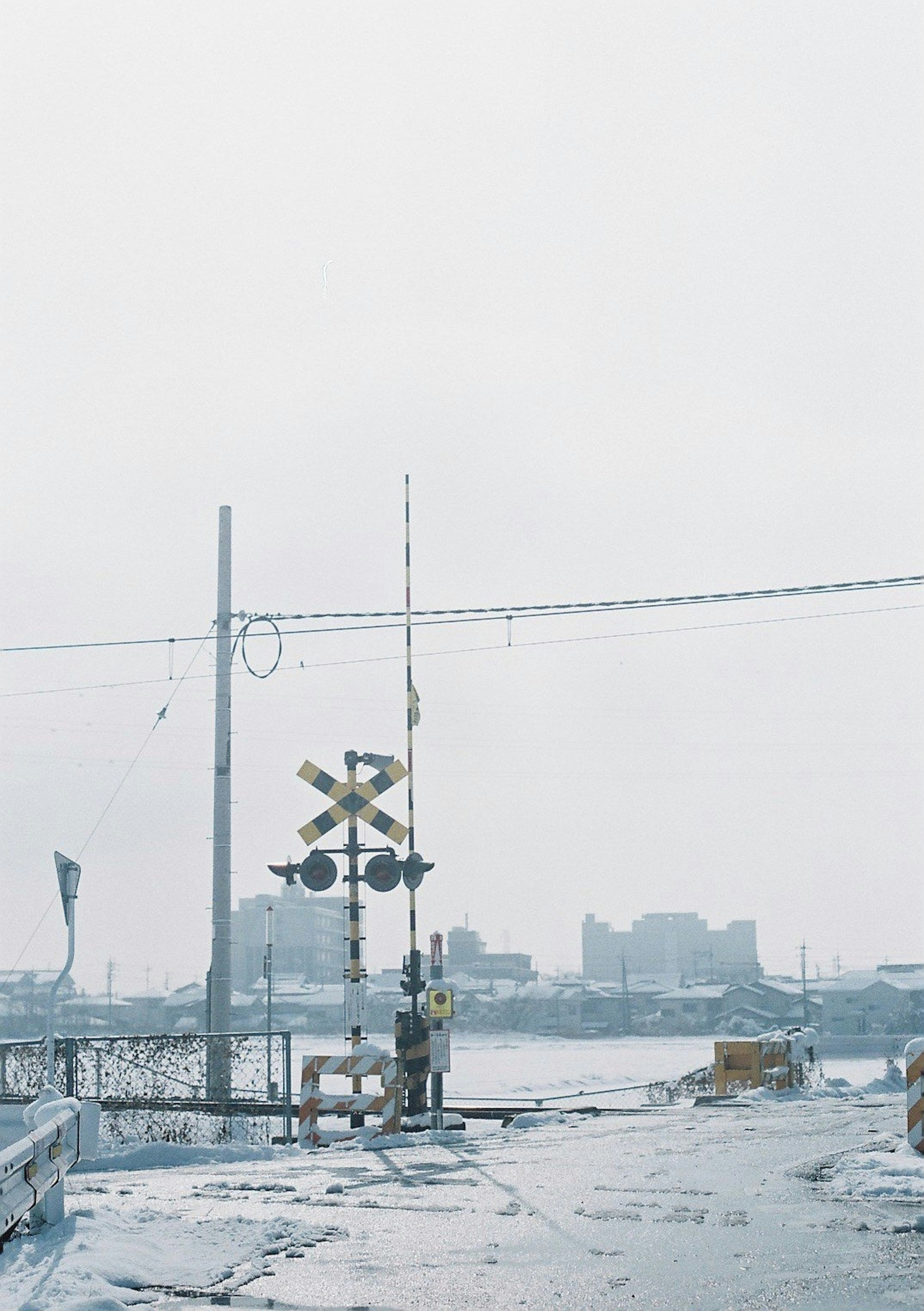 Railroad crossing with a person in snowy weather