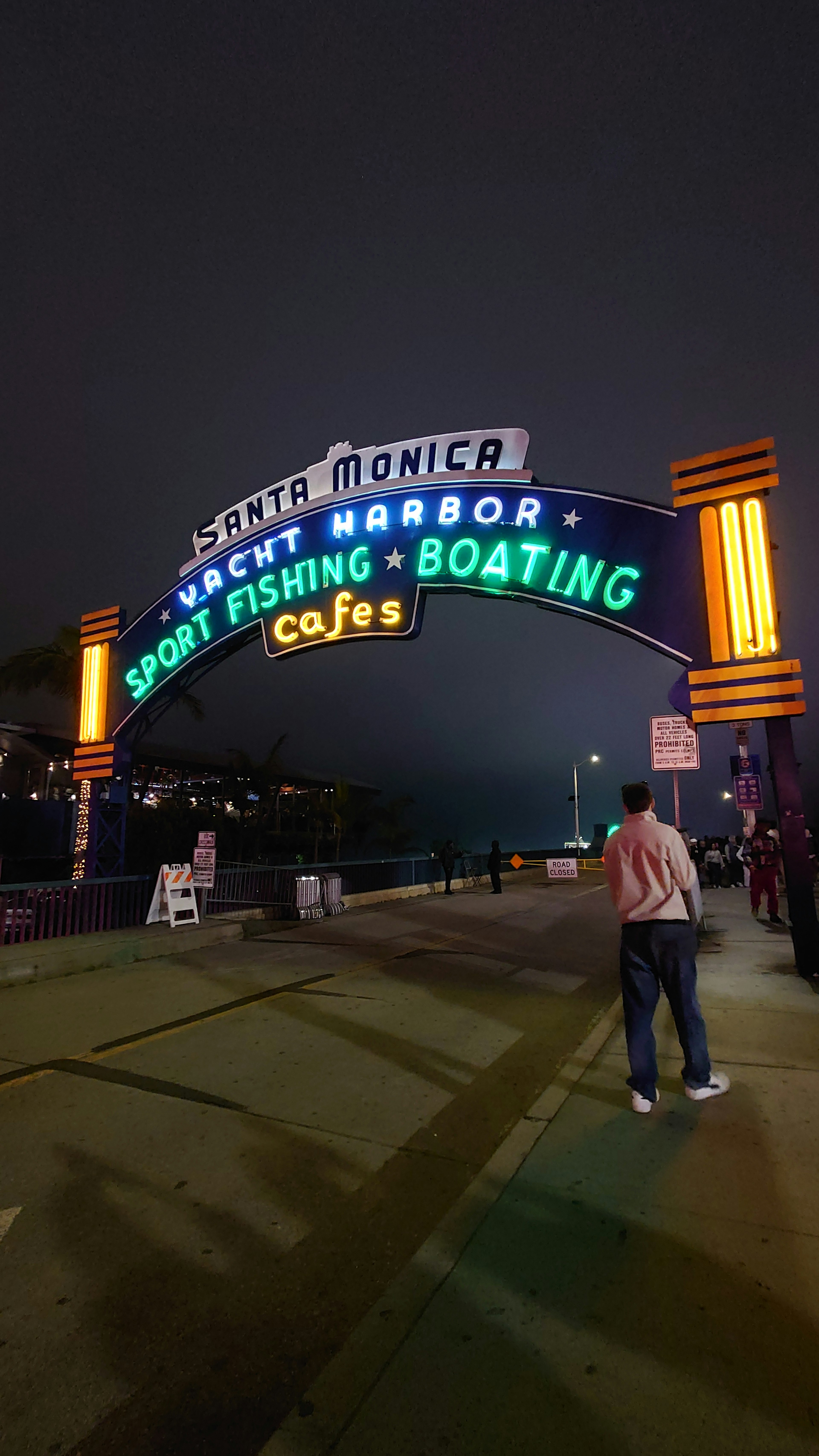 Escena nocturna de Santa Monica con letrero iluminado de pesca deportiva y navegación