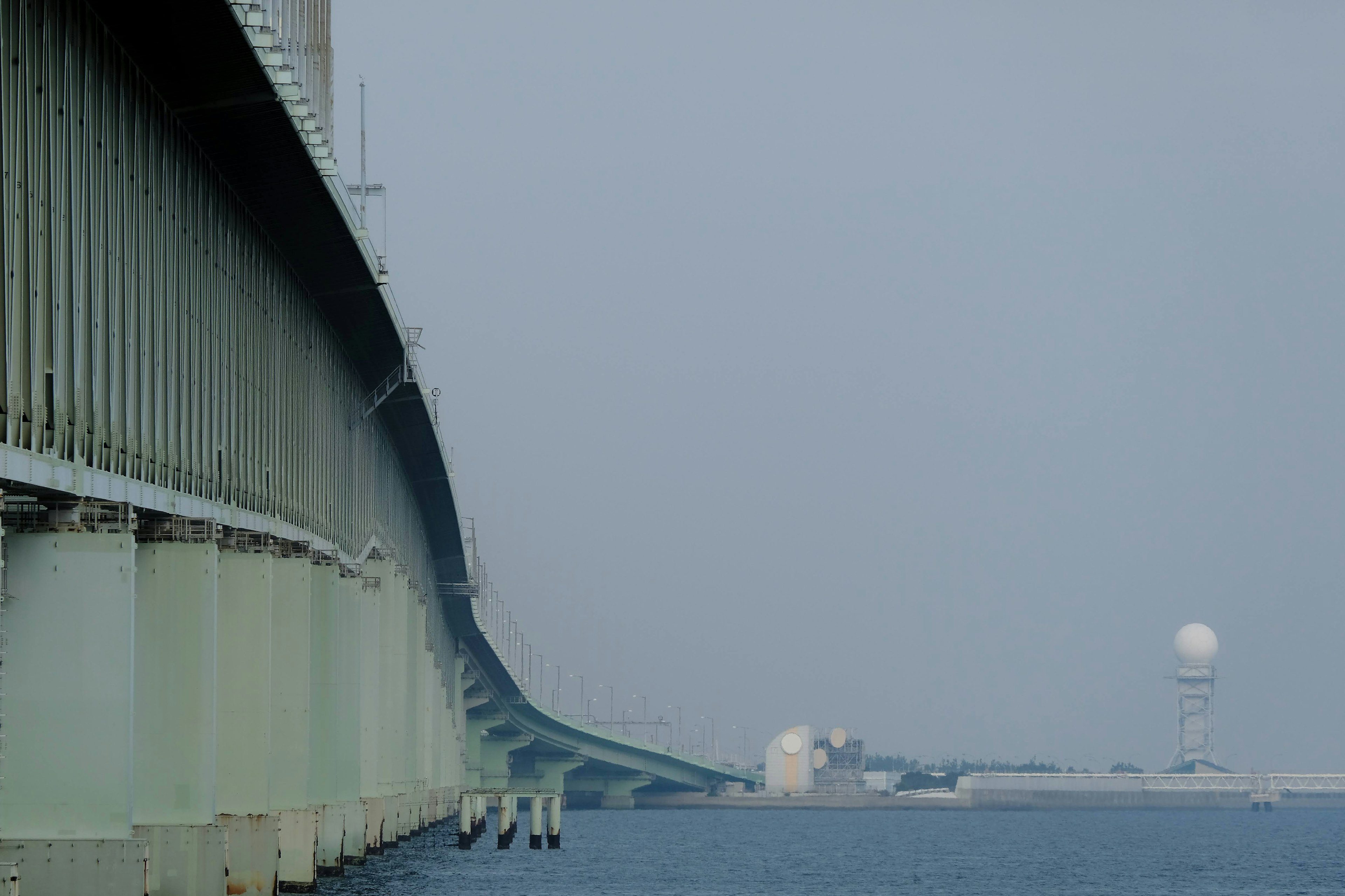 Blick auf eine Brücke über ruhiges Wasser unter einem bewölkten Himmel