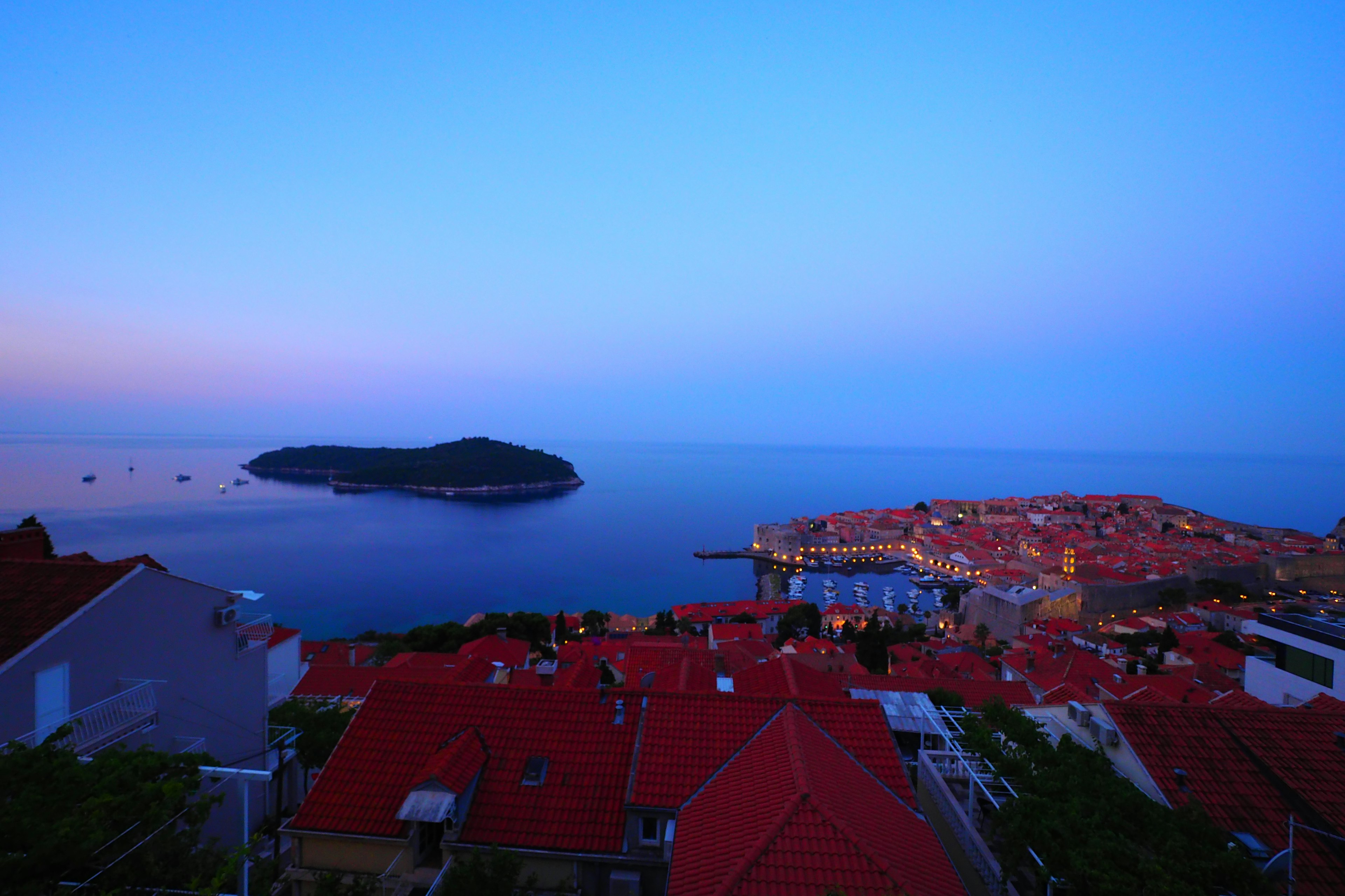 Vista al atardecer de Dubrovnik con casas de techos rojos y mar tranquilo