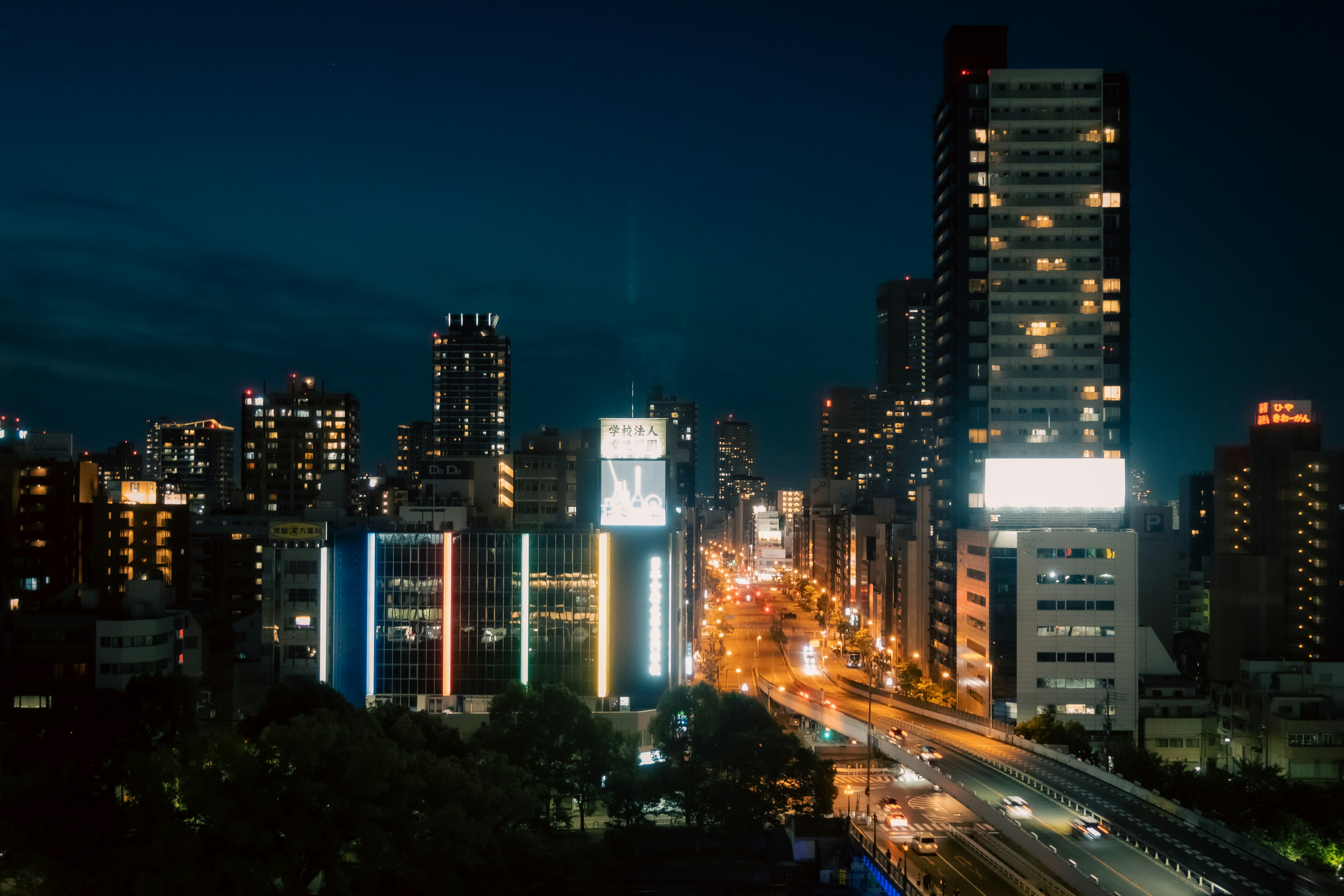 Paesaggio urbano notturno illuminato da luci colorate con alti edifici e strade affollate