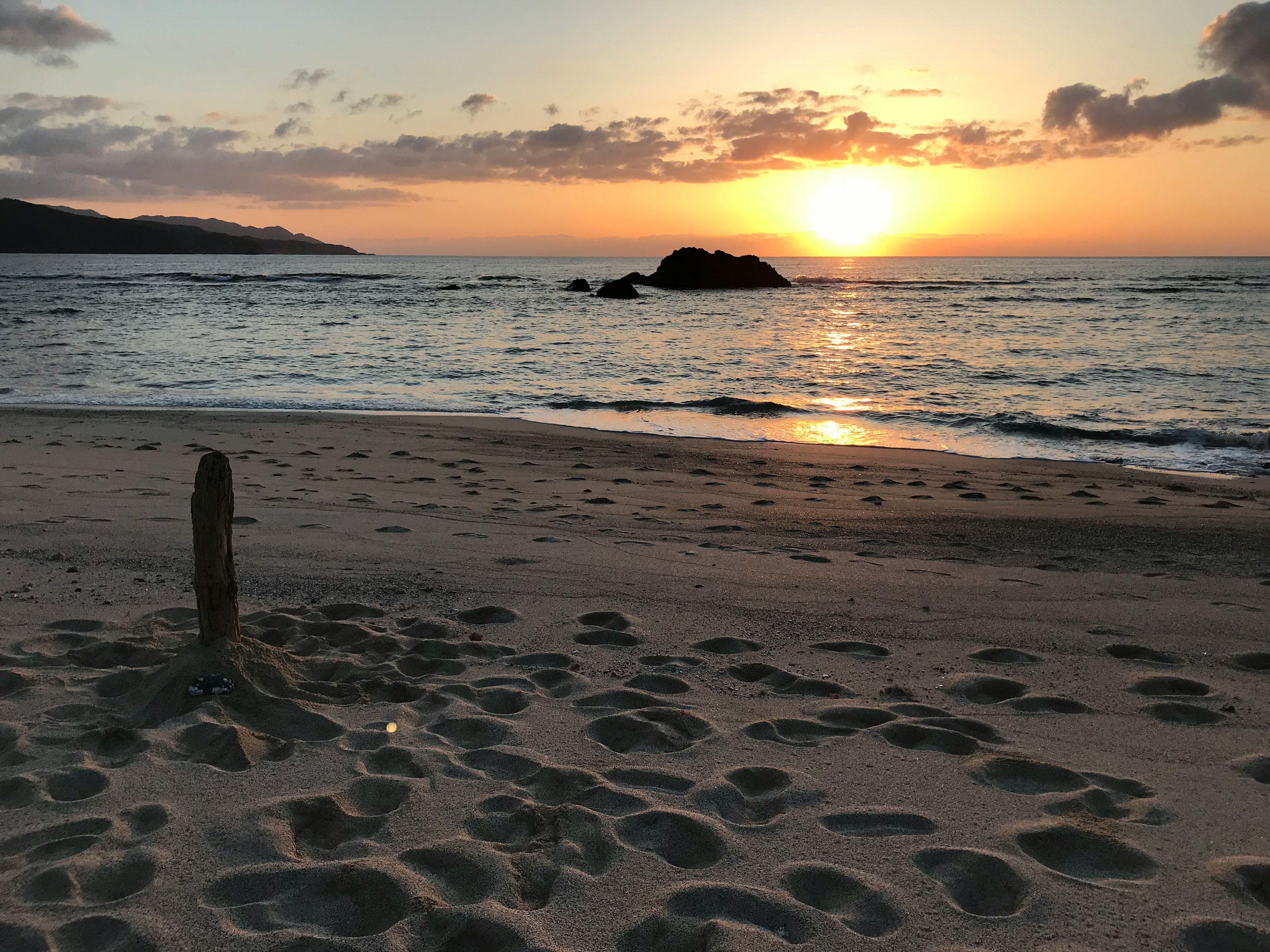 夕日が海に沈むビーチの風景と足跡