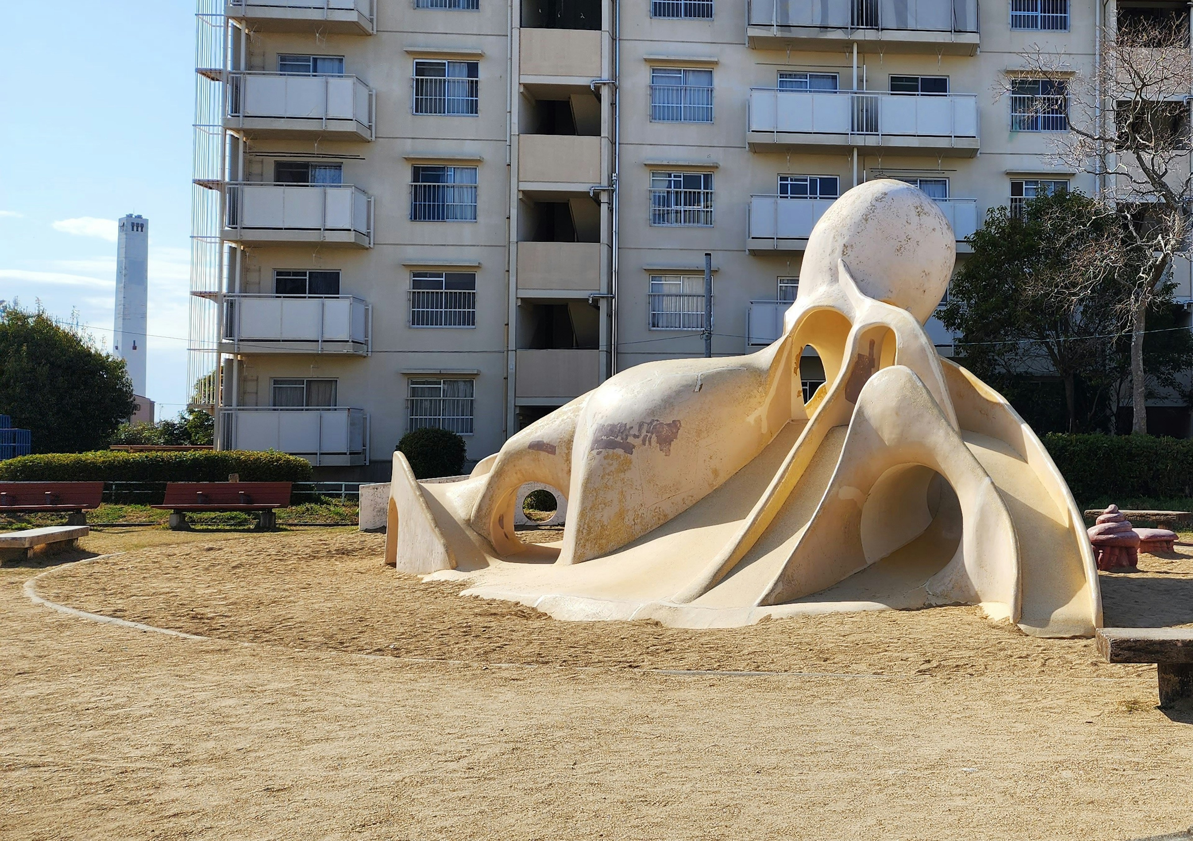 Unique sculpture in a playground with an apartment building in the background