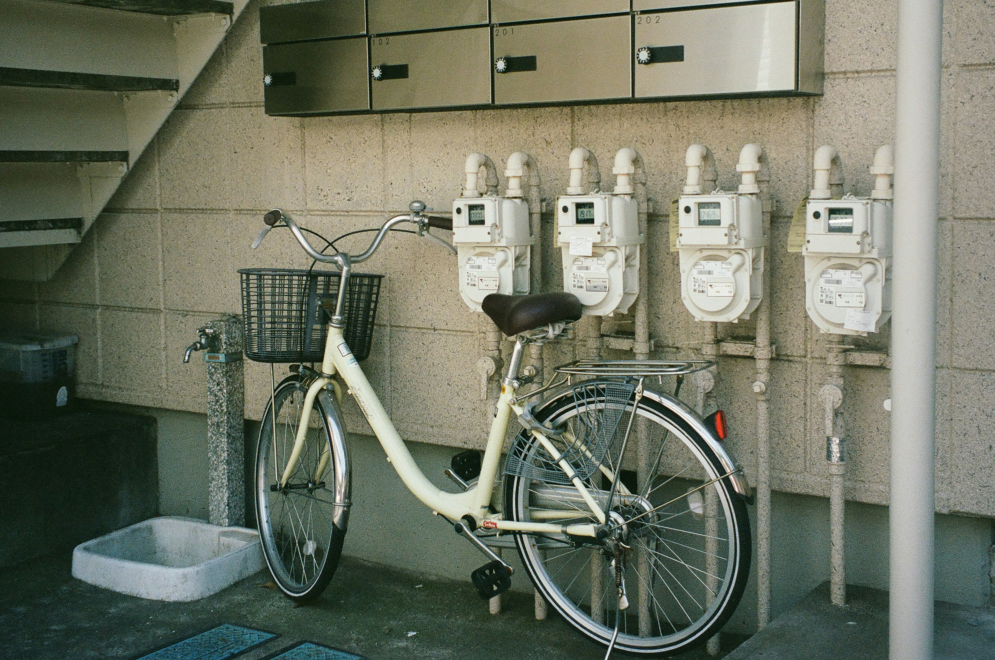 白い自転車とガスメーターが並ぶ壁面の風景