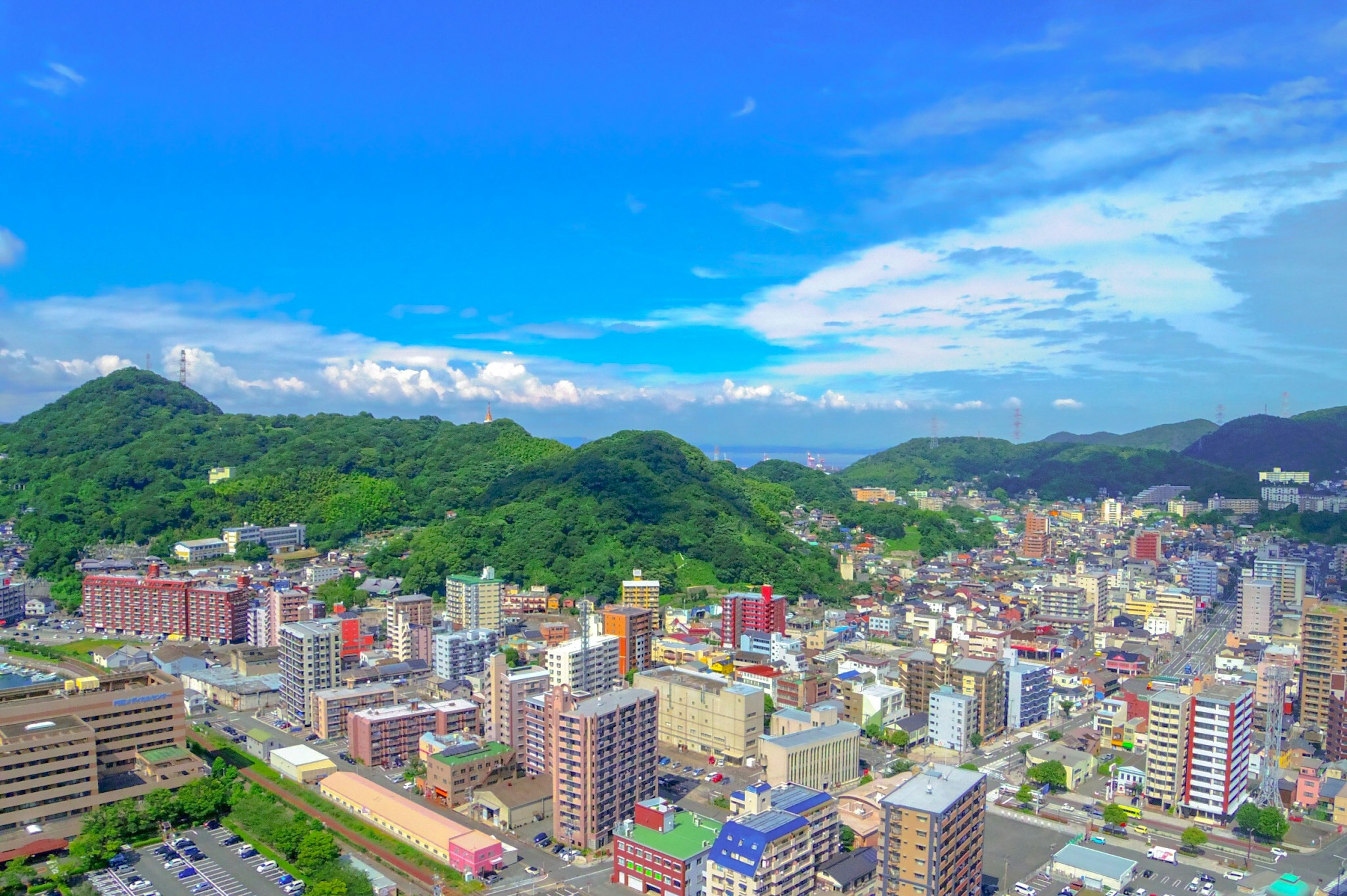 城市的全景，背景是绿色的山丘和蓝天