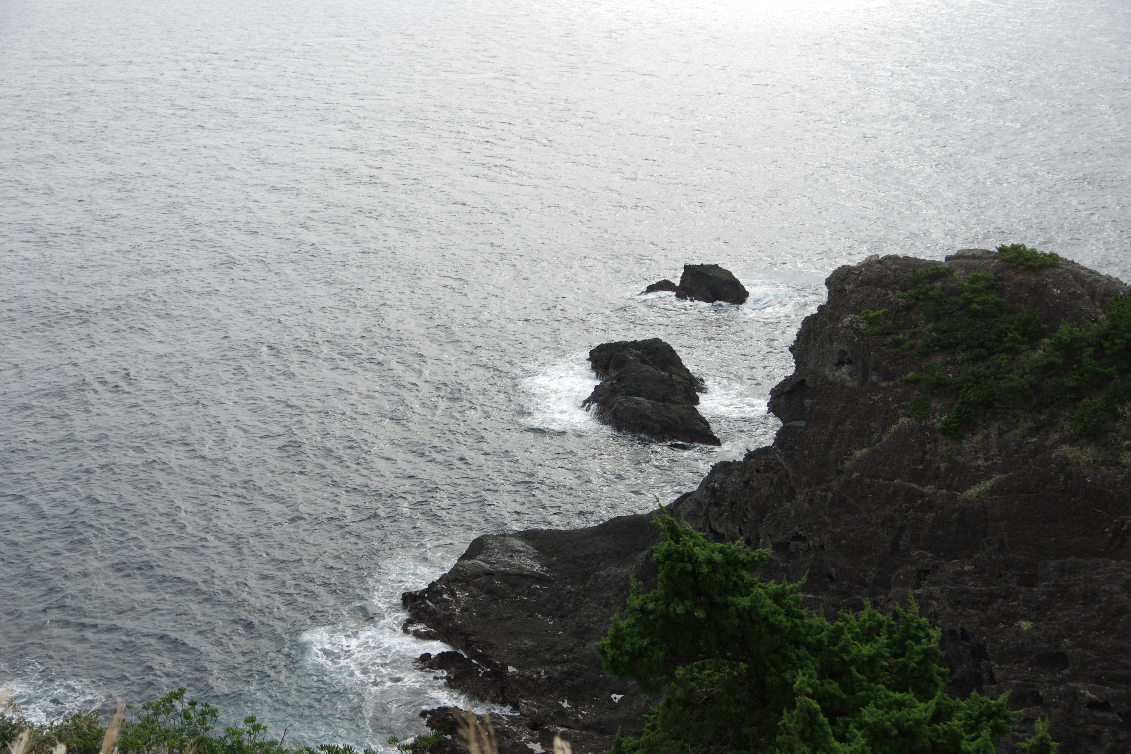 Pemandangan pantai dengan tebing berbatu dan ombak lembut