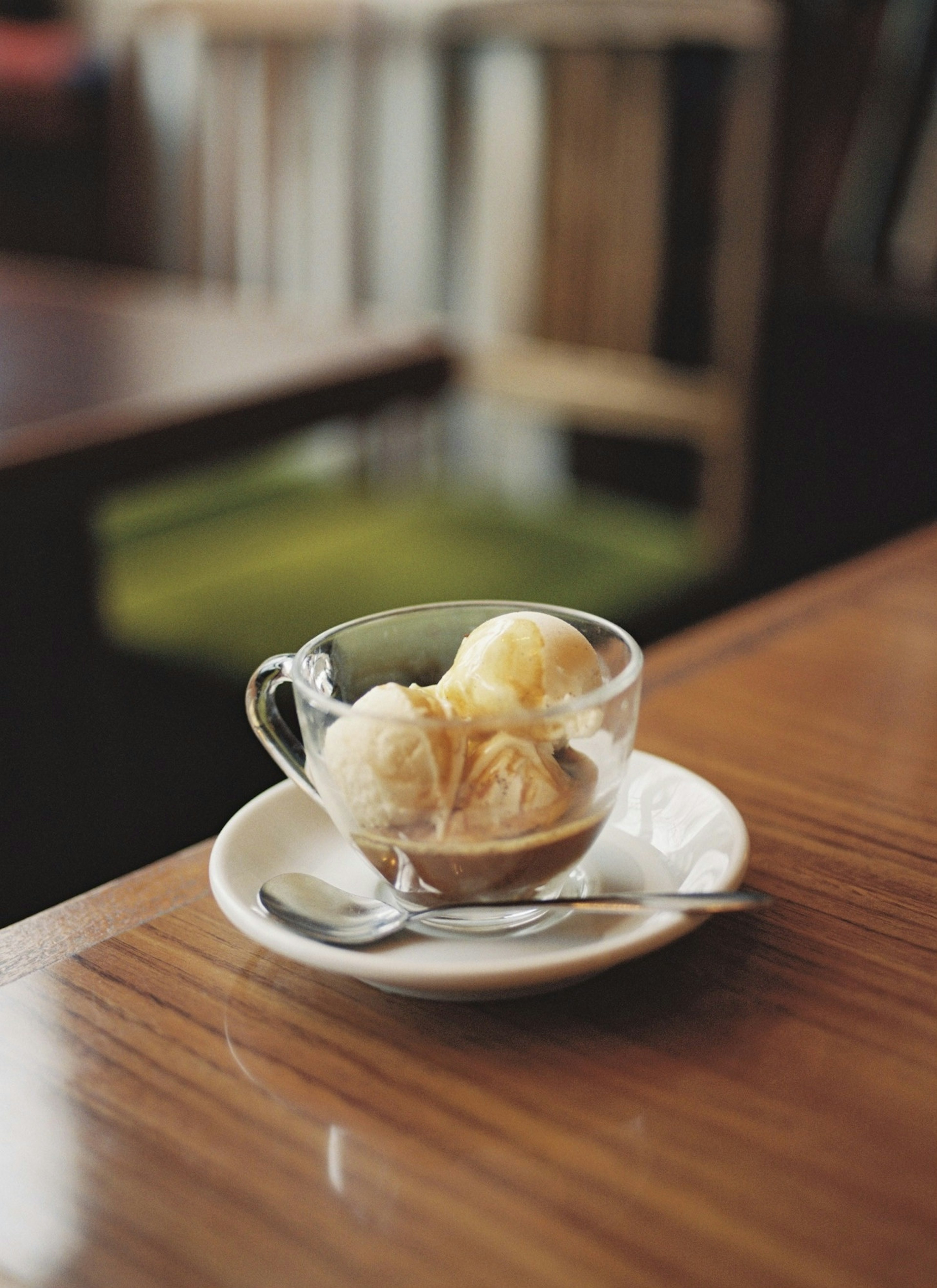 Boules de glace à la vanille dans une tasse transparente sur une soucoupe avec une cuillère