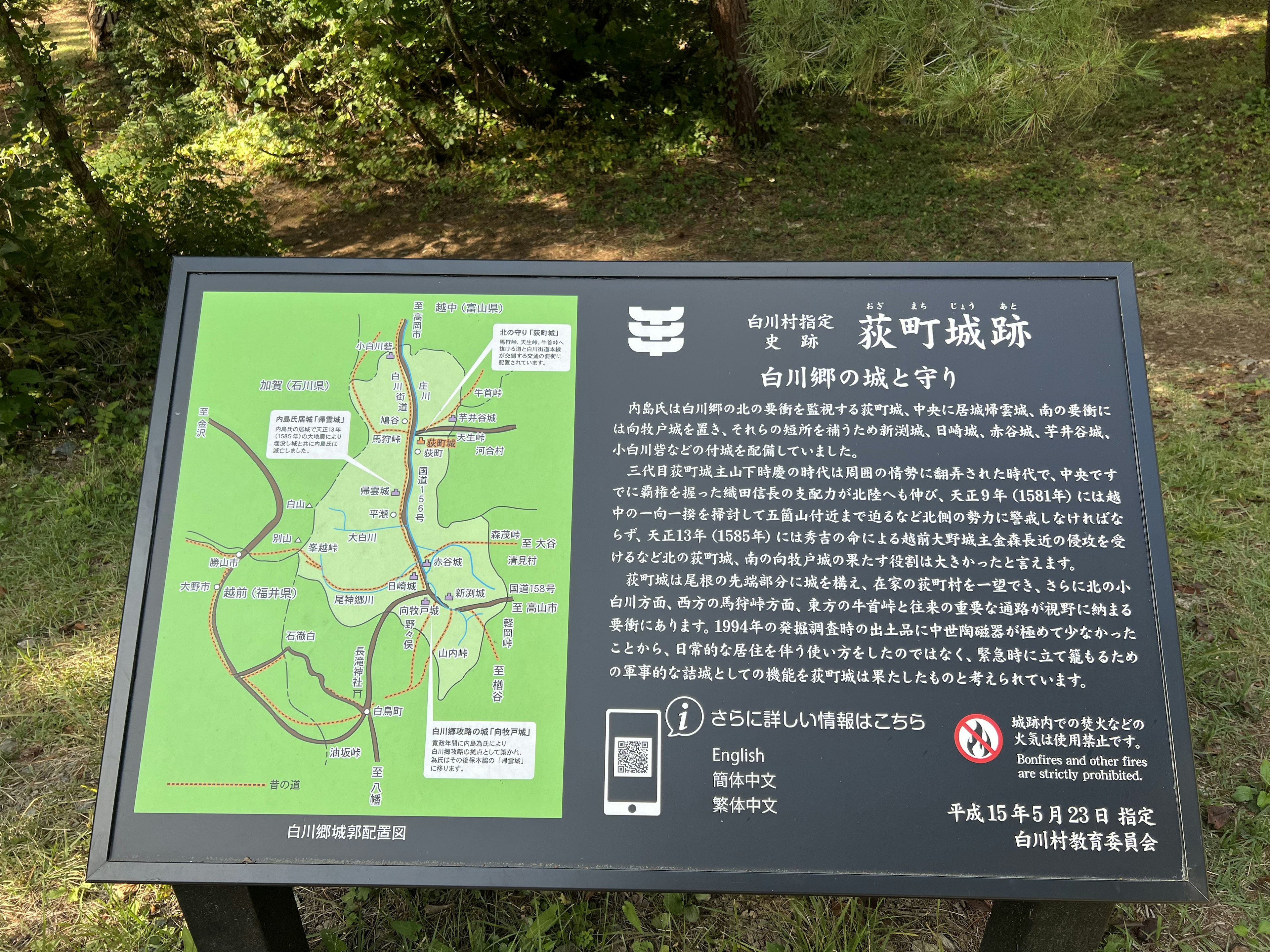 A signboard featuring a green map and information surrounded by trees